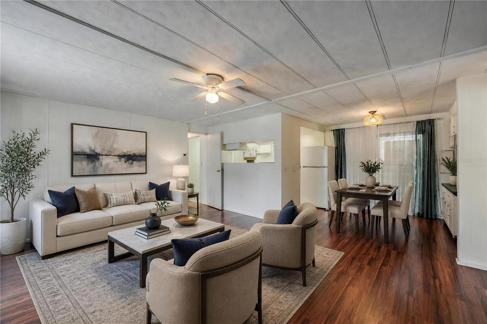 Virtually Staged - Wide-angle view highlights the open flow between the living, dining, and kitchen spaces, complemented by natural light from the large window. - 128 KON TIKI TER, PORT ORANGE