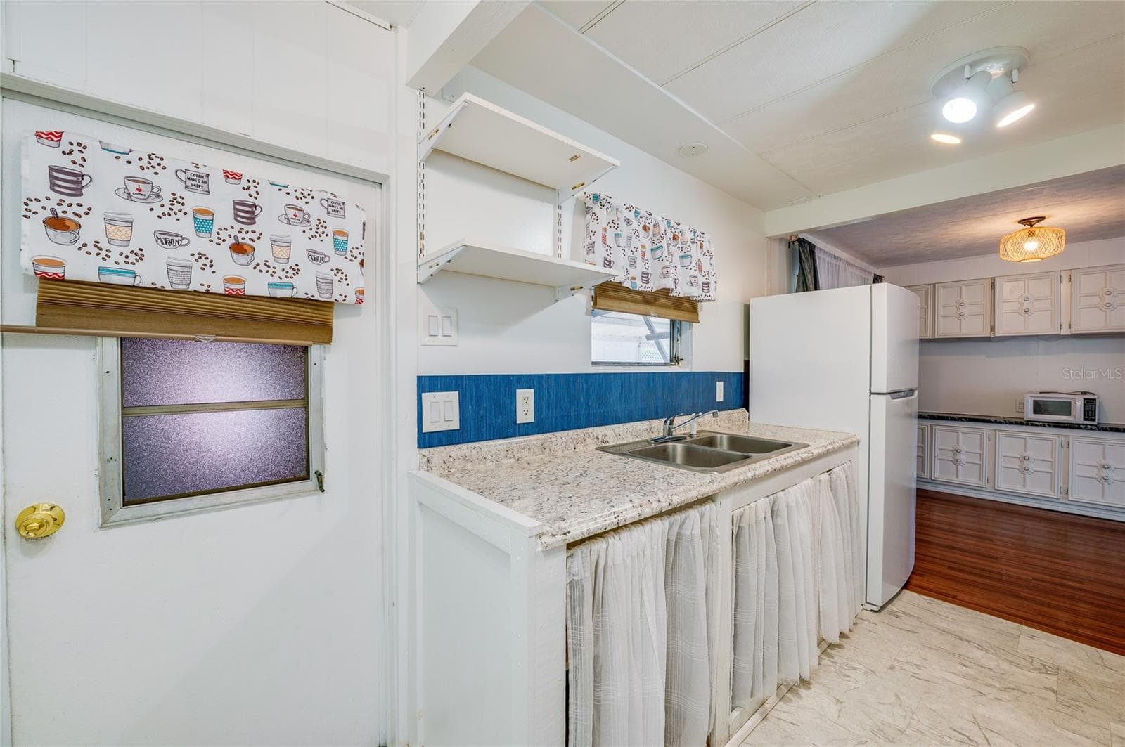 Additional kitchen view showcases the long countertop and sink area, open shelving, and convenient connection to the adjacent dining space. - 128 KON TIKI TER, PORT ORANGE