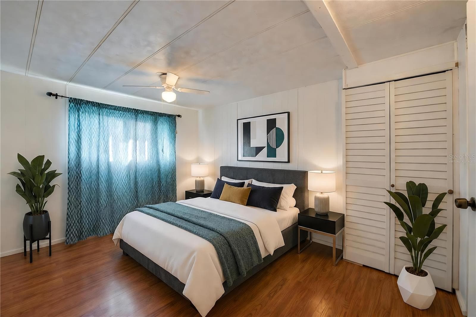Virtually Staged - Bright, versatile bedroom with paneled walls, a ceiling fan with light, a large window for natural light, and a louvered-door closet. - 128 KON TIKI TER, PORT ORANGE