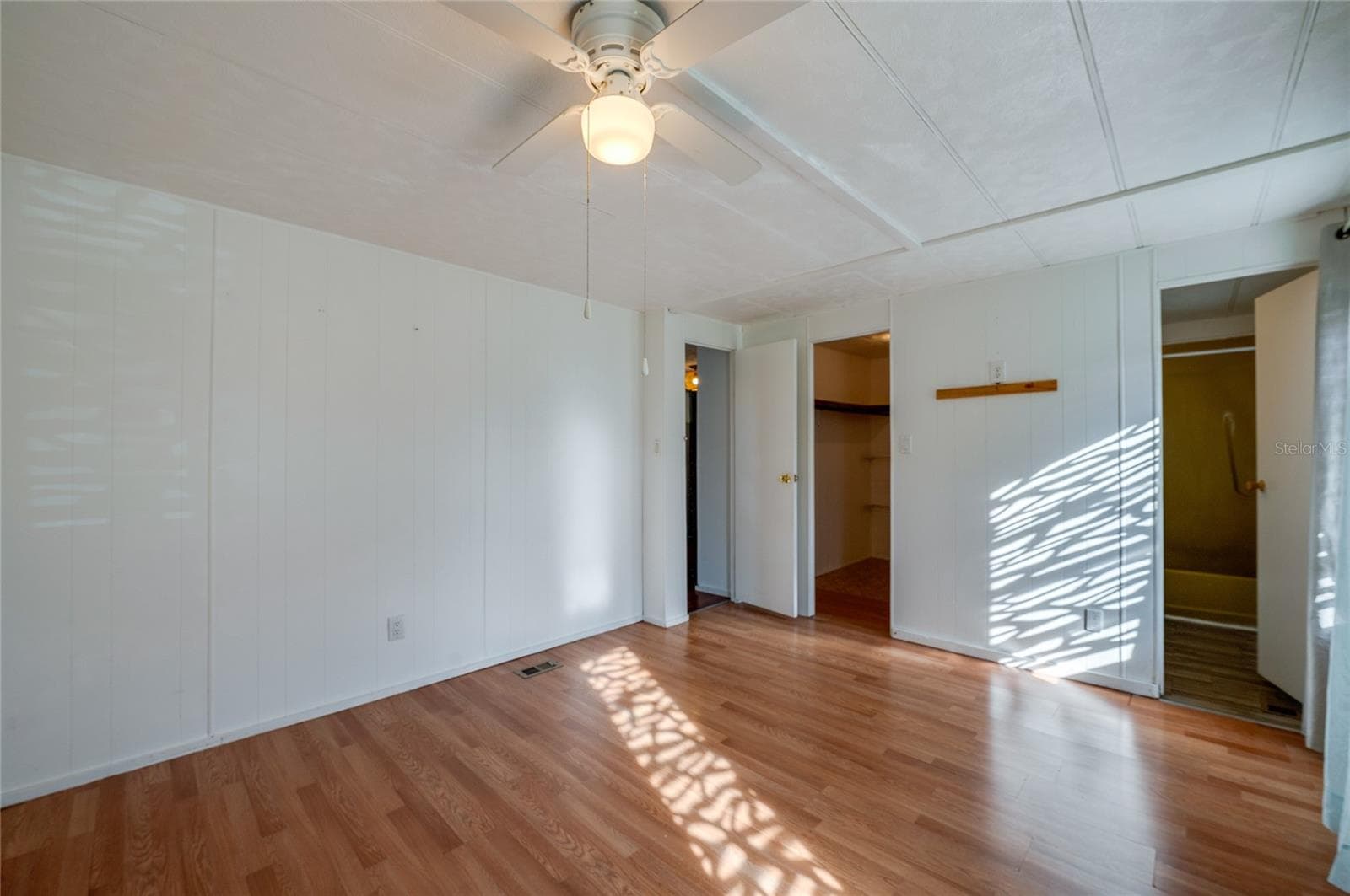 Additional view highlights the room’s open floor area, ceiling fan, and convenient access to a walk-in closet and adjoining bathroom. - 128 KON TIKI TER, PORT ORANGE
