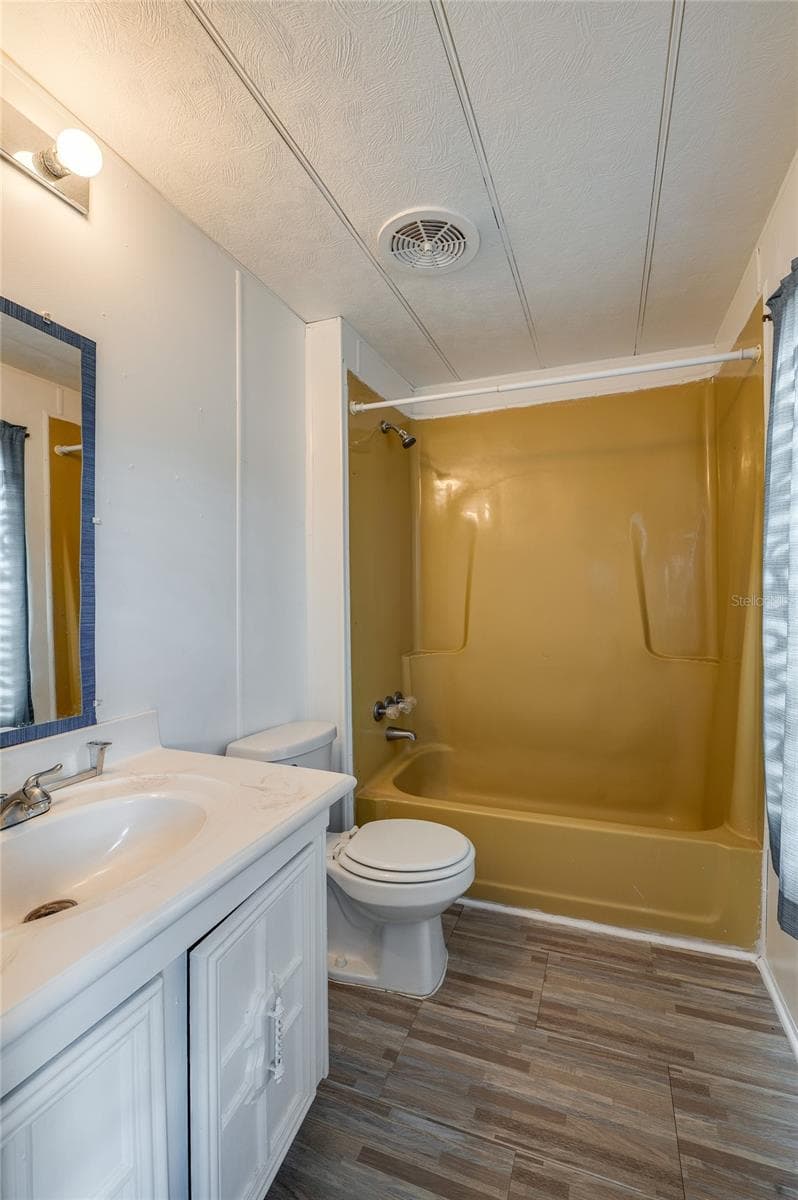 Full bathroom features a tub/shower combination, vanity with storage, and a window providing natural light. - 128 KON TIKI TER, PORT ORANGE