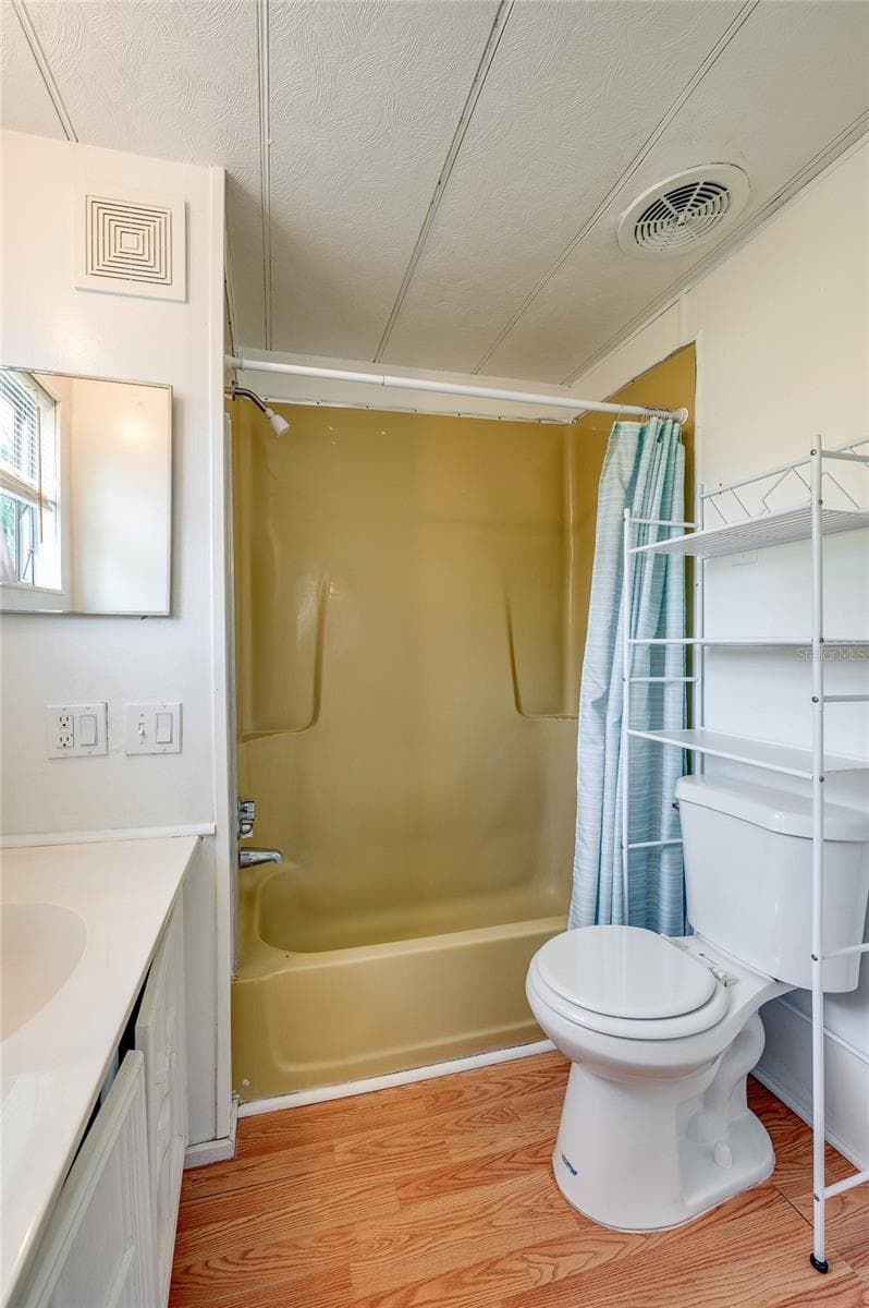 Full bathroom with a tub/shower combination, vanity, window for natural light, and additional over-toilet storage. - 128 KON TIKI TER, PORT ORANGE