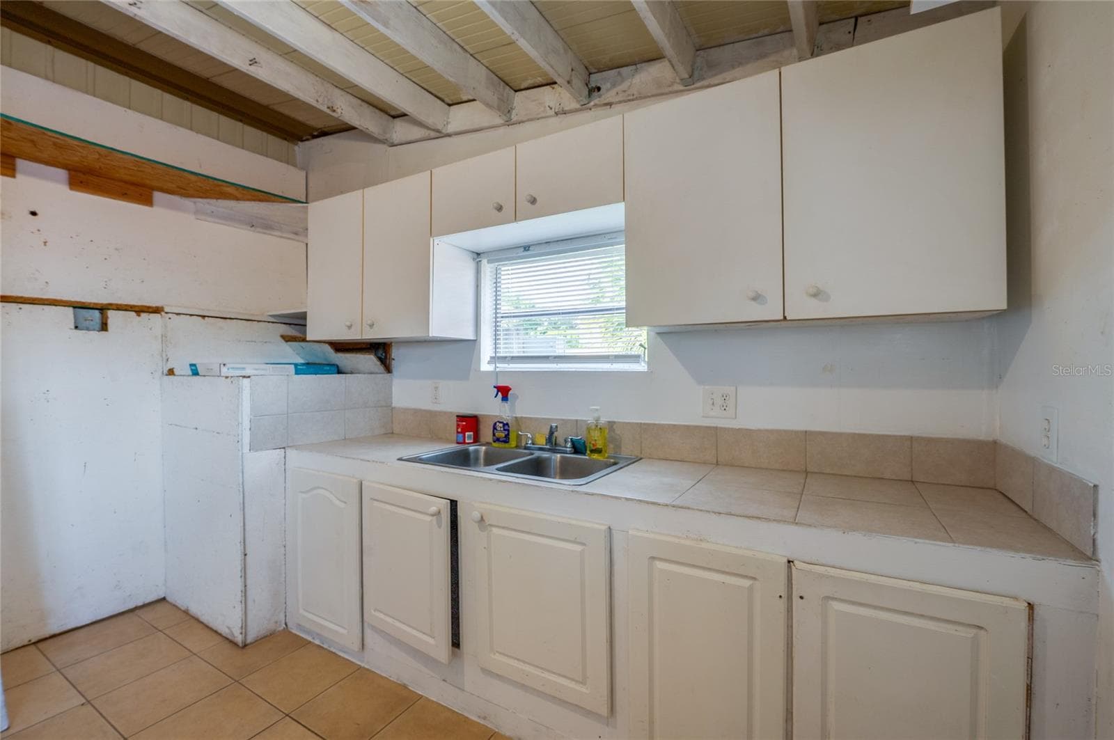 Dedicated utility space includes a double-basin sink, countertop workspace, upper and lower cabinetry, and a window above the sink. - 128 KON TIKI TER, PORT ORANGE