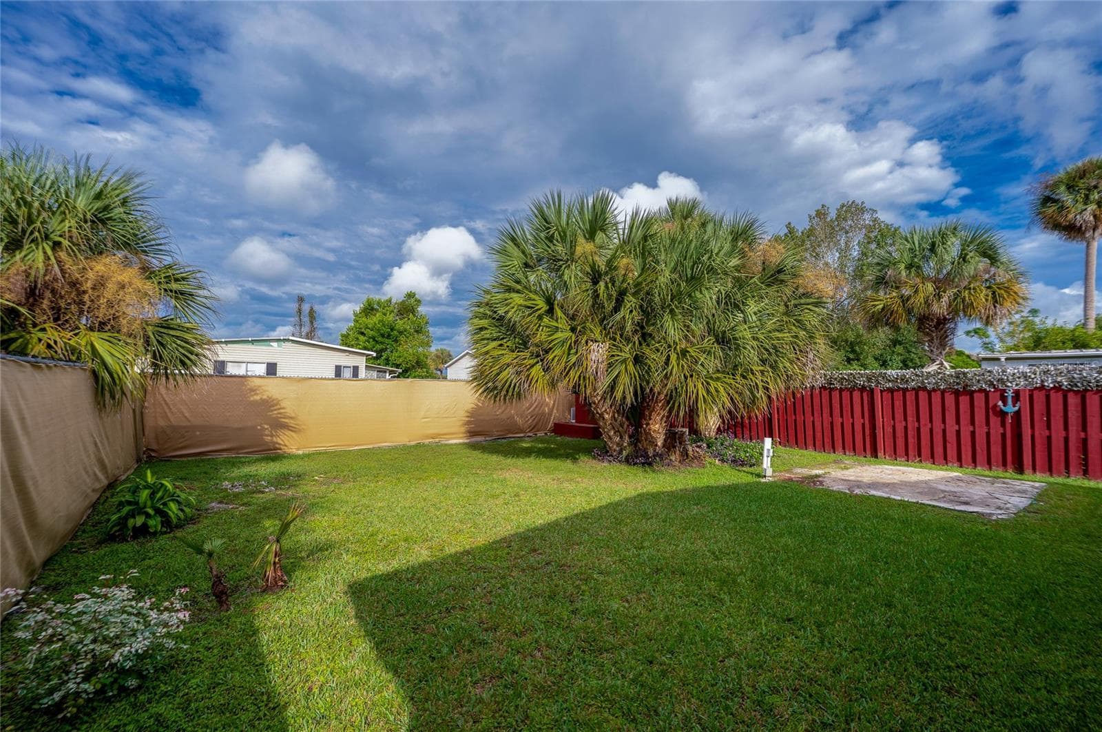 Another view showcases the open lawn and mature palms, providing flexible outdoor space for relaxing, gardening, or recreation. - 128 KON TIKI TER, PORT ORANGE