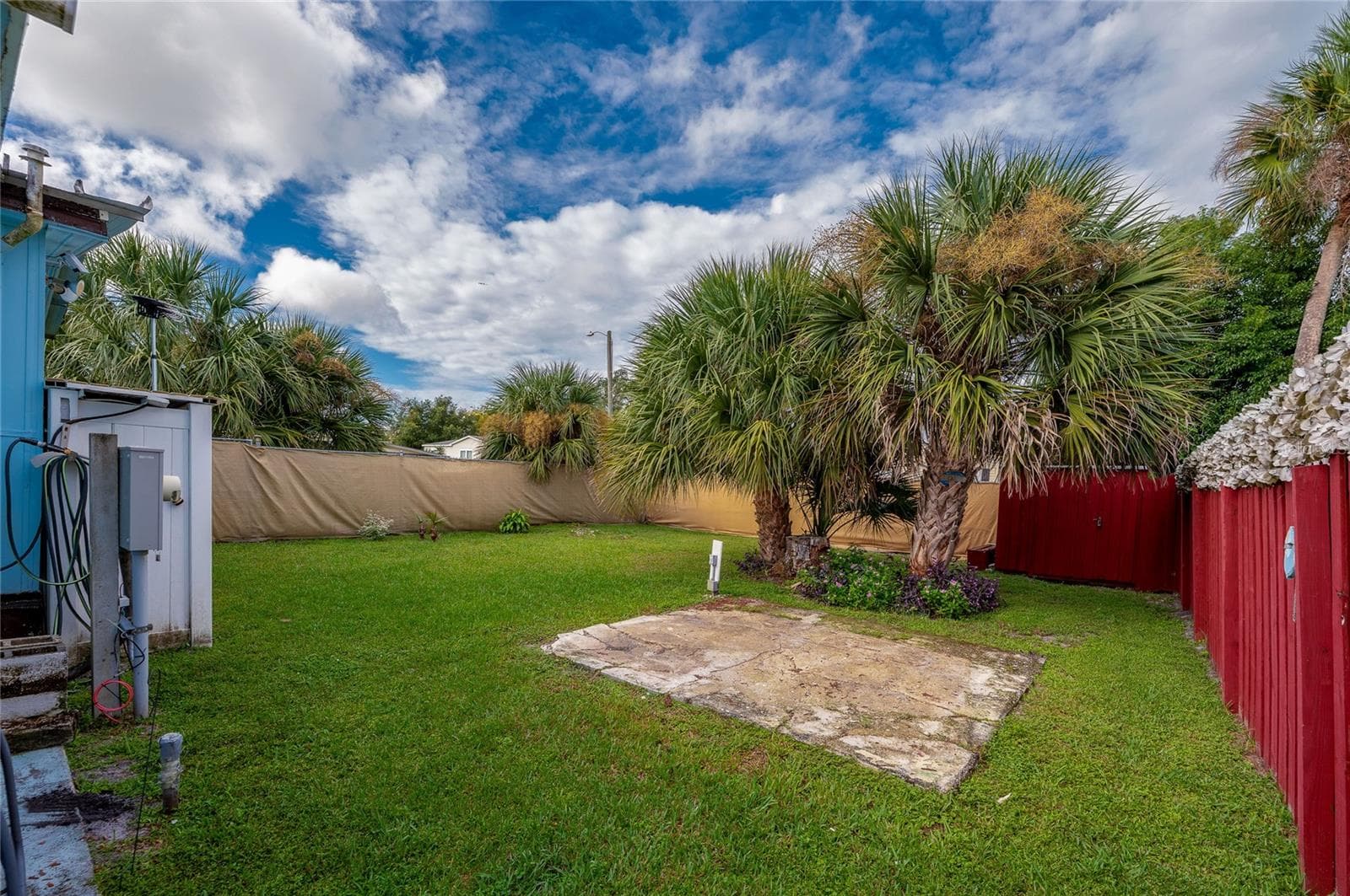Spacious grassy backyard offers plenty of open outdoor space, complemented by mature palms and perimeter screening for added privacy. - 128 KON TIKI TER, PORT ORANGE