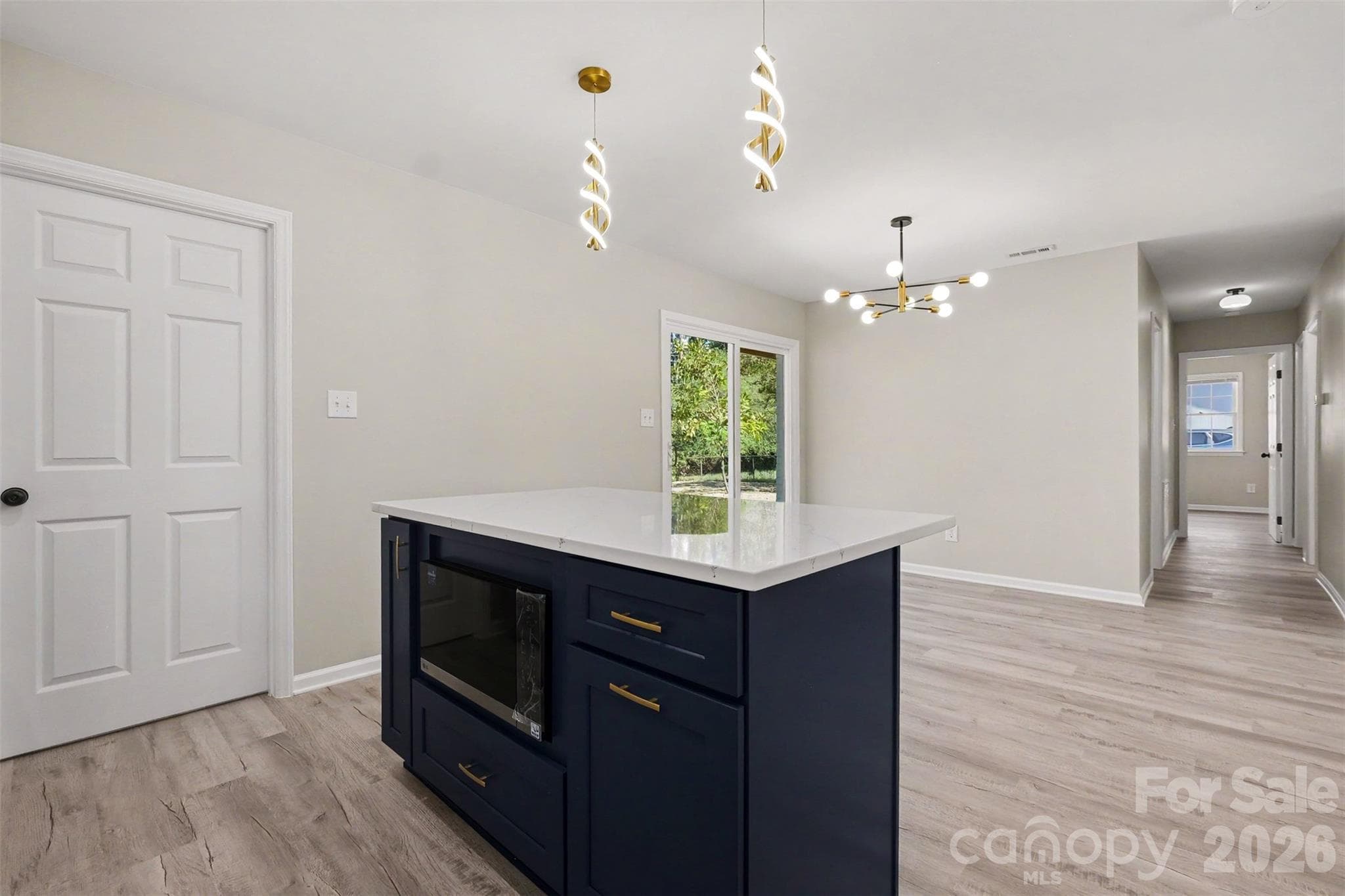Kitchen island detail with built-in microwave and open view extending toward the dining area and bedroom hallway - 3801 Hillock Court, Charlotte