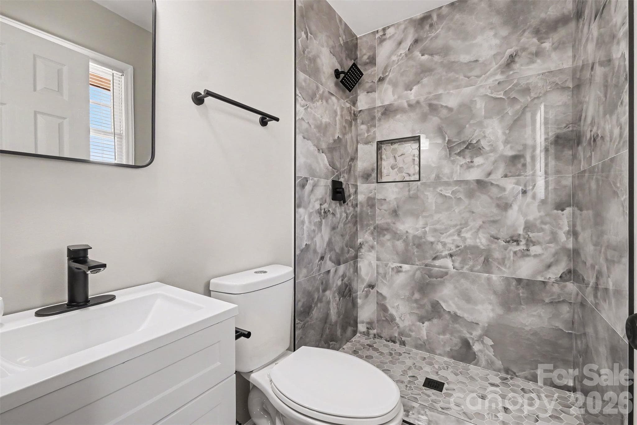 Luxurious primary ensuite featuring a custom walk-in shower with floor-to-ceiling dark porcelain tile, modern vanity, and sleek black fixtures. - 3801 Hillock Court, Charlotte
