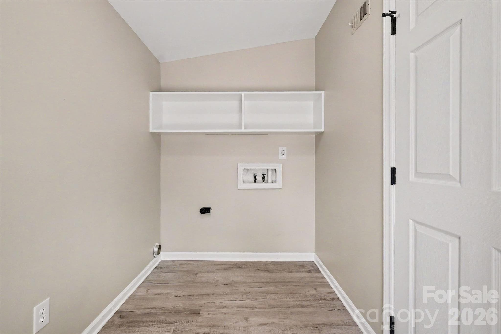 Spacious dedicated laundry room featuring built-in upper storage shelving, new vinyl flooring, and washer/dryer hookups. - 3801 Hillock Court, Charlotte