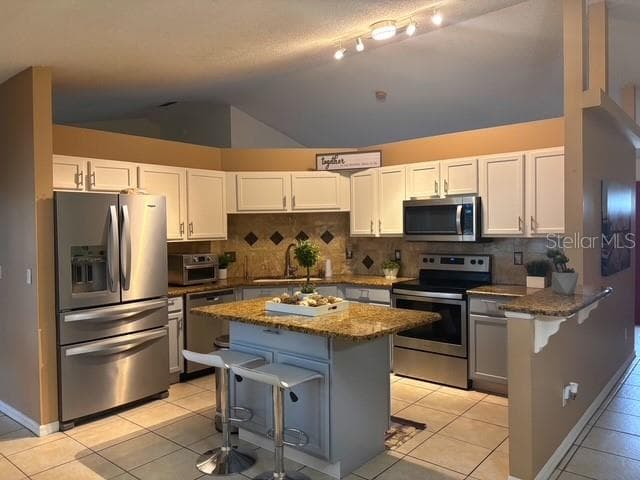 Kitchen view white cabinets with solid counters, island, stainless steel appliances, splash, and breakfast counter. - 4030 SANTA BARBARA RD, KISSIMMEE