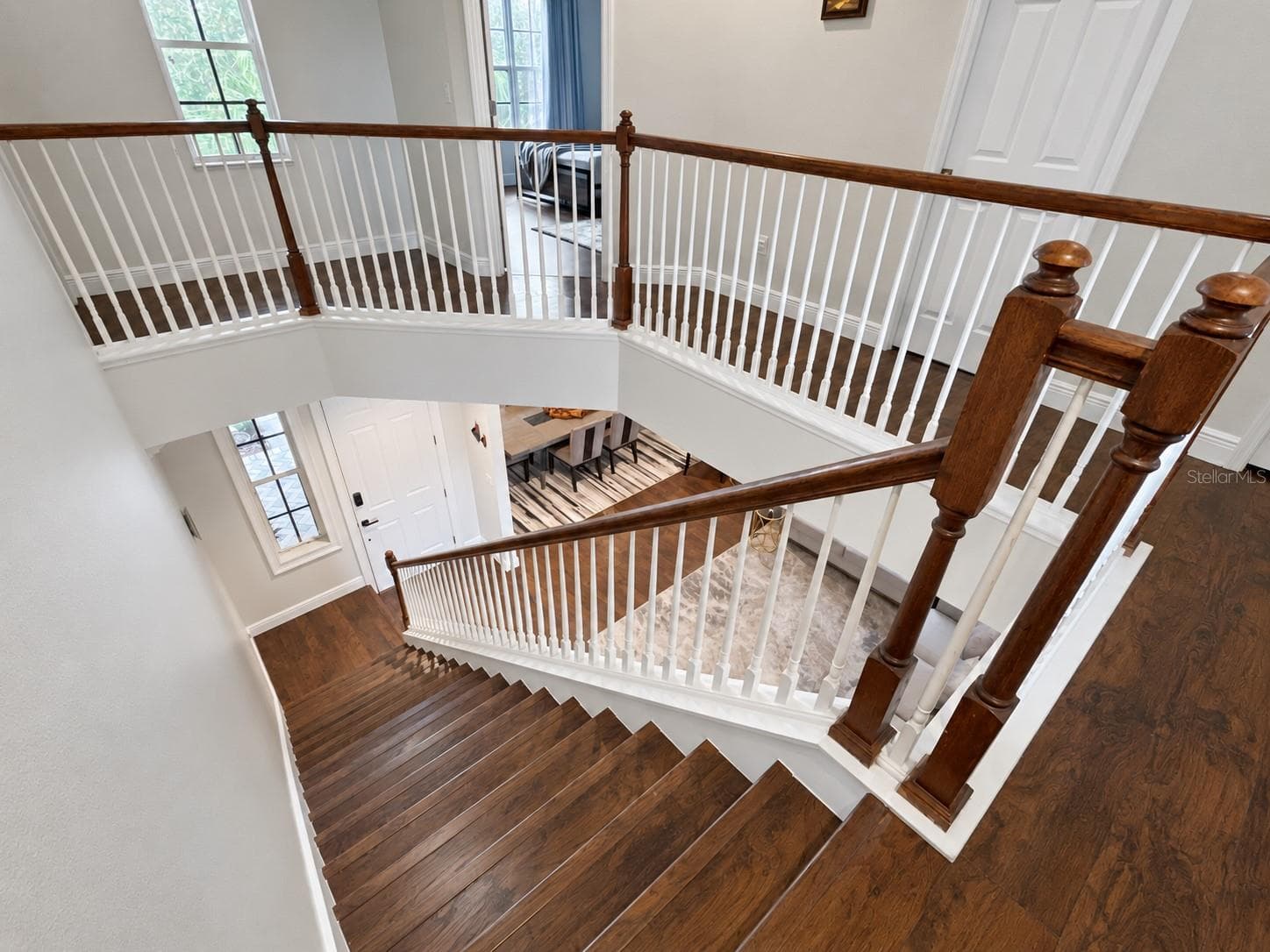 An open staircase with wood treads, white balusters, and a matching wood handrail connects the two levels. The upper landing overlooks the entrance, with tall windows bringing light into the circulation spaces. - 11117 ANCIENT FUTURES DR, TAMPA