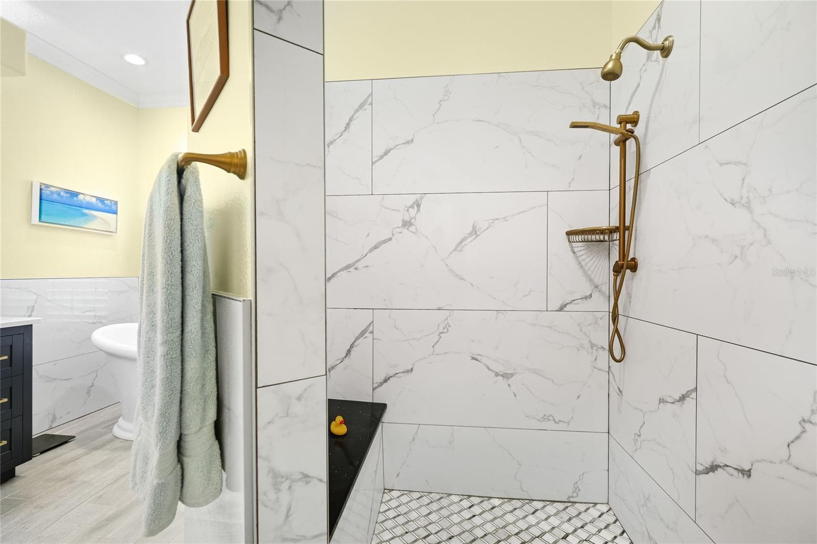 Primary bathroom walk-in shower with custom tile, updated plumbing fixtures, and built-in bench. - 3306 LITTLE COUNTRY RD, PARRISH