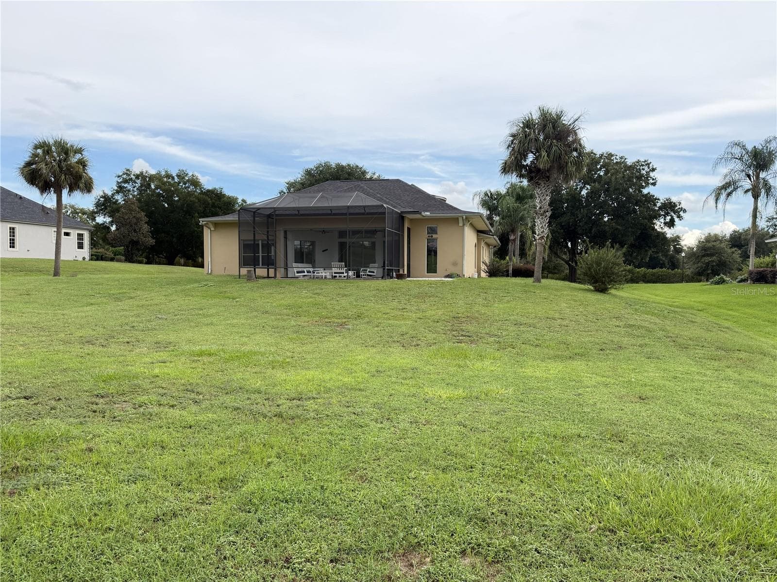 Rear lawn of the expansive 0.63-acre homesite view of screened lanai. - 39539 HARBOR HILLS BLVD, LADY LAKE