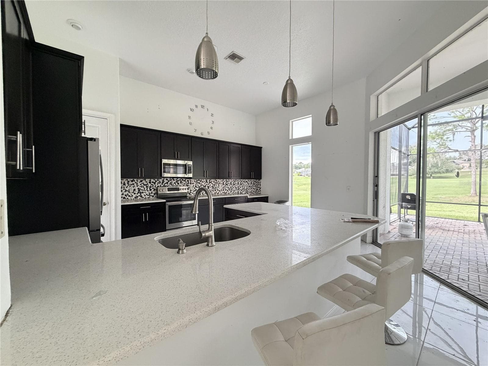 Kitchen with extended breakfast bar, pendant lights, and lanai access. - 39539 HARBOR HILLS BLVD, LADY LAKE
