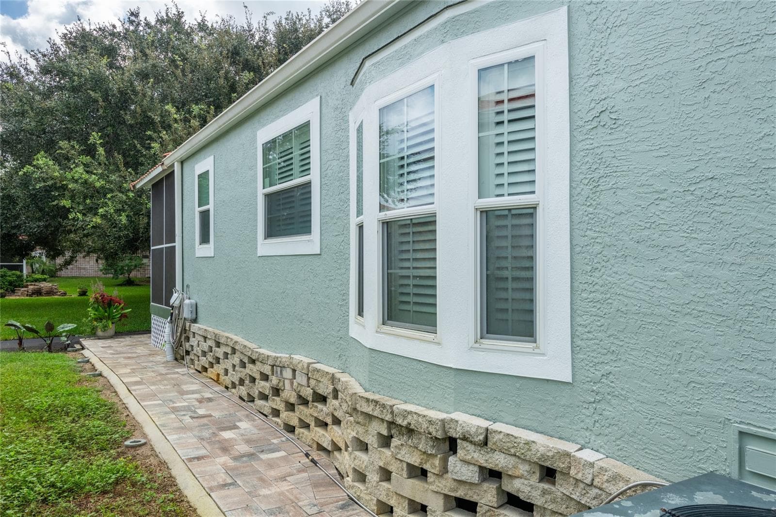 View showing custom pavers on the left side that wraps around to the back steps and screen lanai. - 6544 LA MESA RD, LAND O LAKES