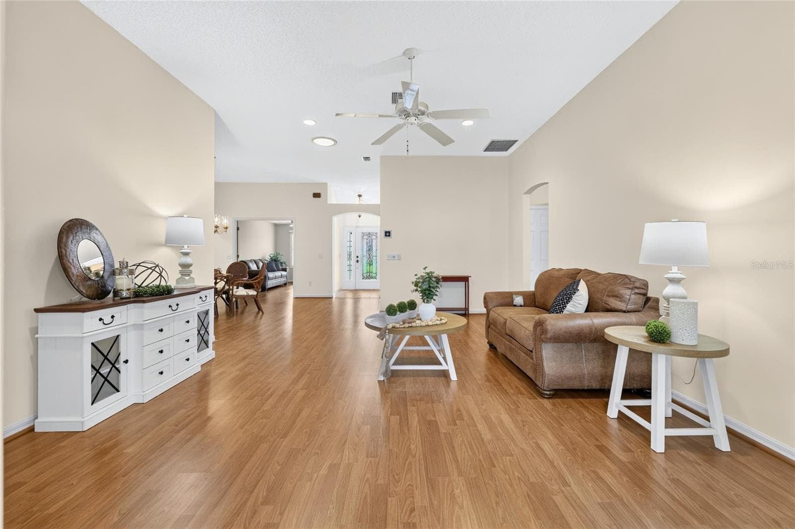 Expansive living area showcasing an open floor plan, vaulted ceilings, abundant wall space, and a seamless connection to the dining area and foyer. - 3064 BURBANK LN, THE VILLAGES