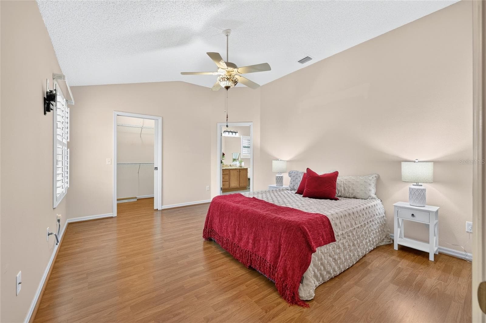 Spacious primary suite featuring vaulted ceilings, wood-look flooring, a decorative ceiling fan, and convenient access to the walk-in closet and en-suite bathroom. - 3064 BURBANK LN, THE VILLAGES