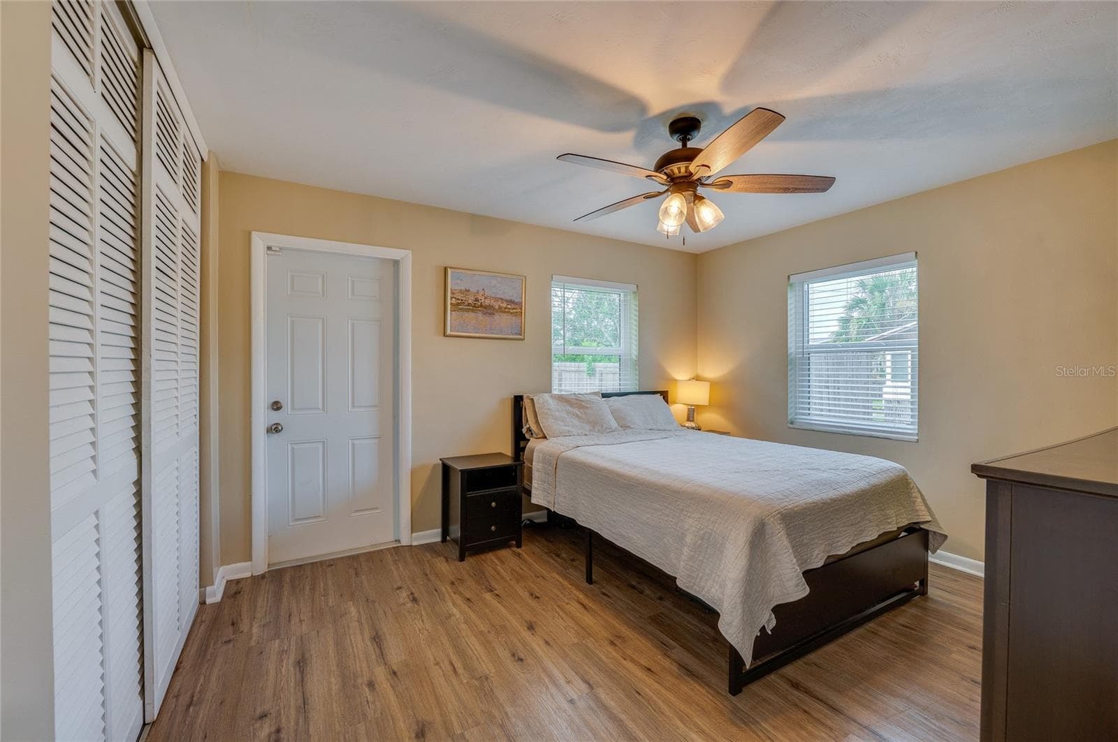 Cozy bedroom offering LVP flooring, louvered closet doors, neutral walls, and a ceiling fan with integrated lighting. - 605 E NORMANDY BLVD, DELTONA