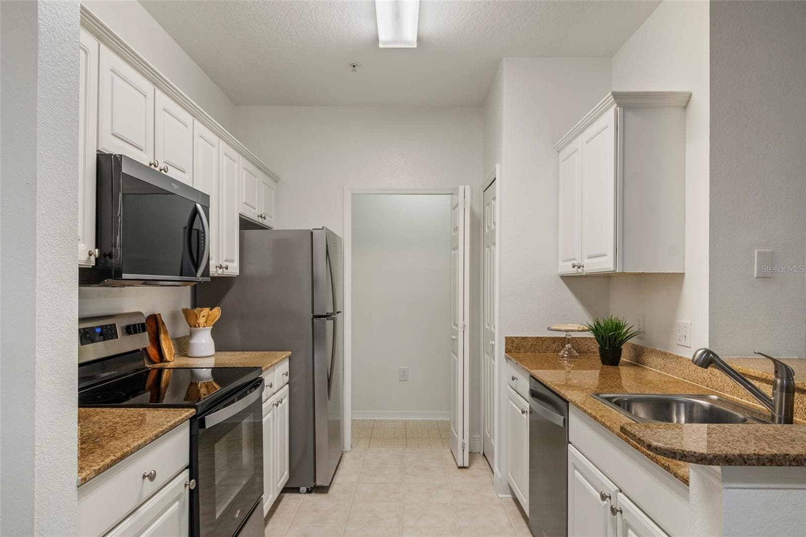Direct view as you enter the galley kitchen and look to the far end which is the dedicated laundry room with bi fold door for days when that last load does not get done. - 1300 EASTERN PECAN PL #208, WINTER GARDEN