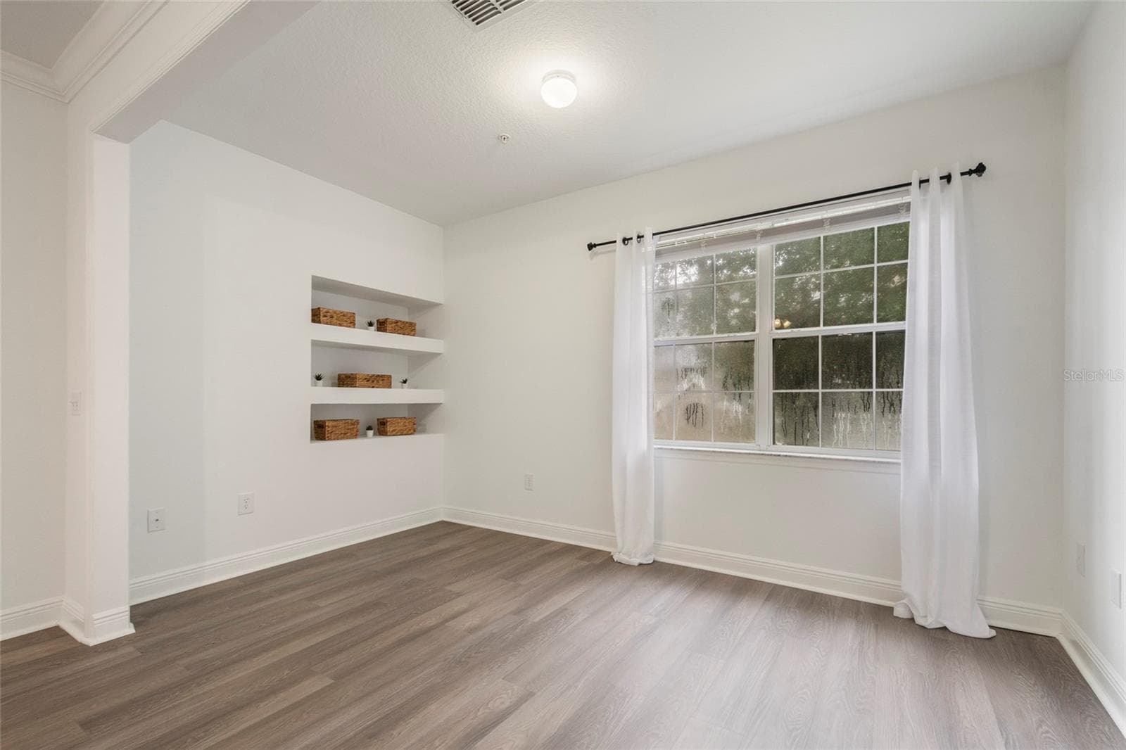 This view shows the built in shelving which would make a great contribution if you chose to dedicate this to a home office or storage space if you chose to make it a flex room for the kids, or work out gear if it became your exercise room. (Drapes do not convey) - 1300 EASTERN PECAN PL #208, WINTER GARDEN