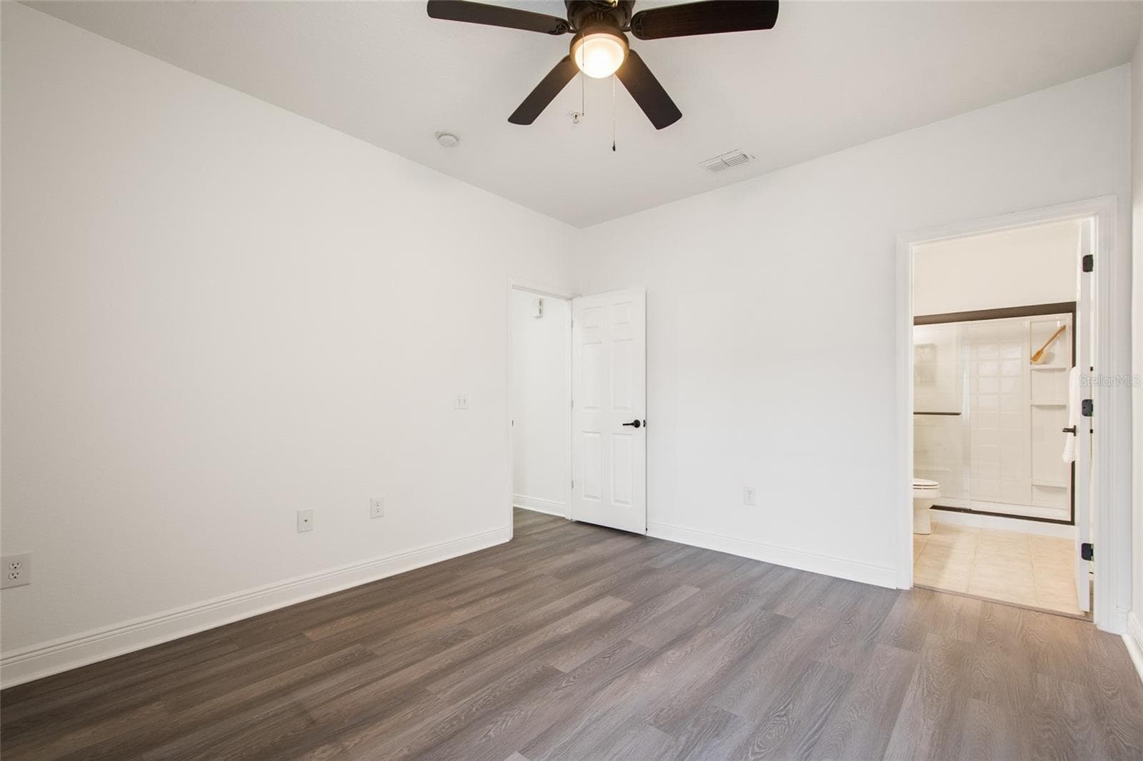 Entering the primary suite note the freshly painted walls, ceiling, trim and doors complemented by the updated ceiling fan, and en suite entrance to the primary bathroom. - 1300 EASTERN PECAN PL #208, WINTER GARDEN