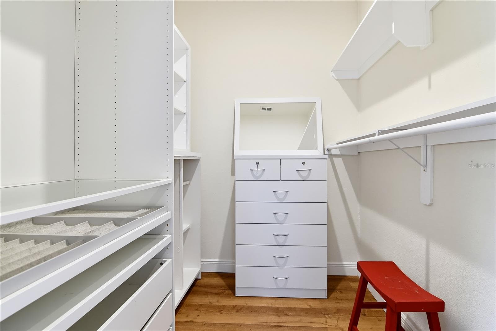 Walk-in primary closet with extensive built-in shelving, hanging space, and drawers. - 1611 CHESTNUT AVE, WINTER PARK