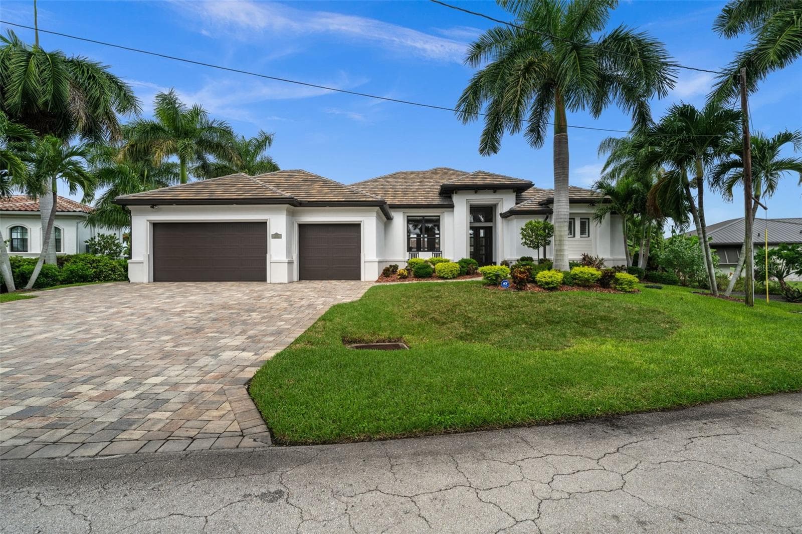 Mature tropical landscaping and tile roof make for a grand entry - 5205 SUNSET CT, CAPE CORAL