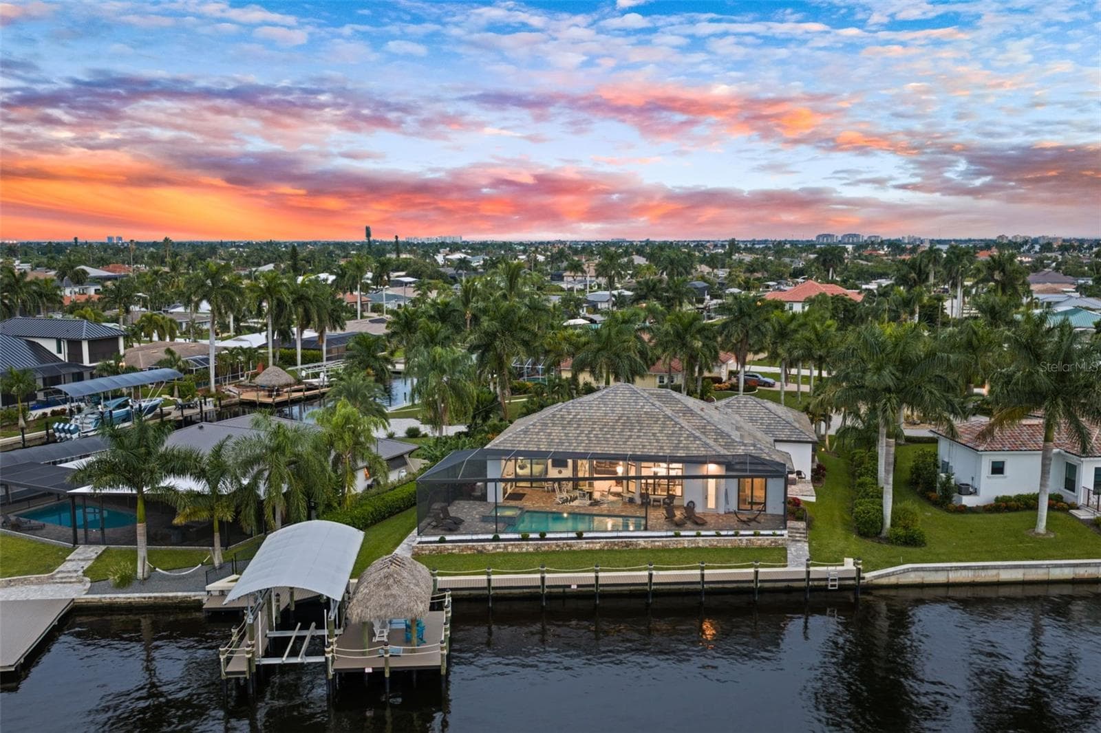 Aerial evening view of the back of the house, plus the dock, tiki and lift - 5205 SUNSET CT, CAPE CORAL