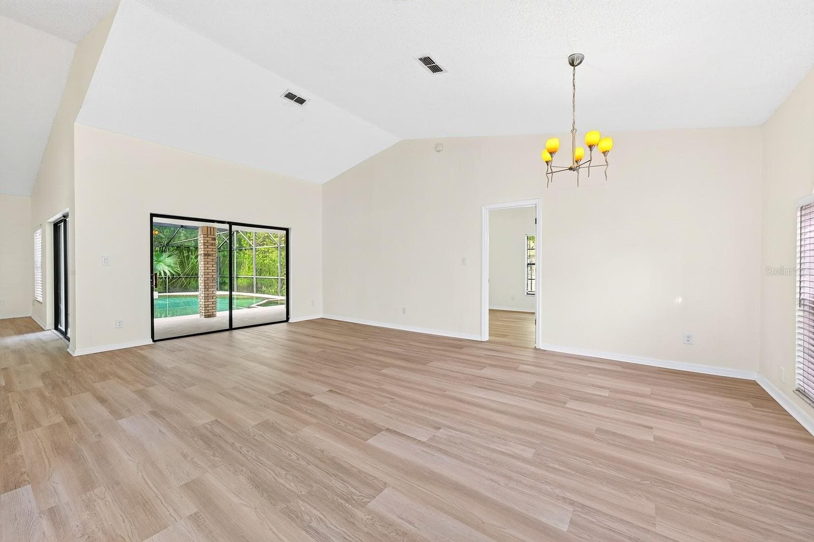 In the Living Room, sliding glass doors open to the PATIO AND POOL AREA—perfect for entertaining or enjoying a relaxed evening at home. - 1003 N MAGEE CREEK CT, OVIEDO