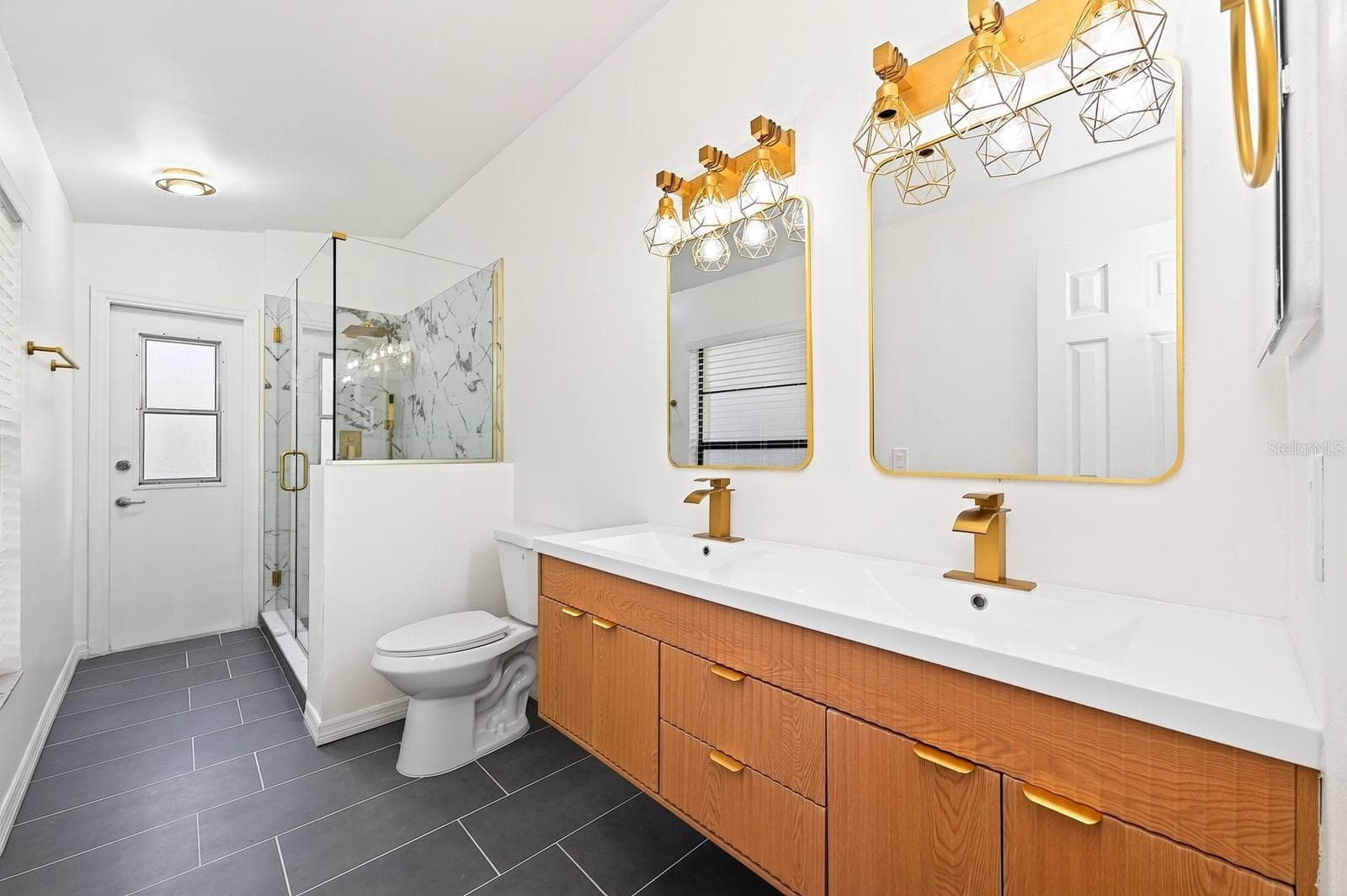 The second full Bath, also COMPLETELY UPDATED IN 2026, features dual sinks, a walk-in shower and a convenient door leading directly to the pool area. - 1003 N MAGEE CREEK CT, OVIEDO