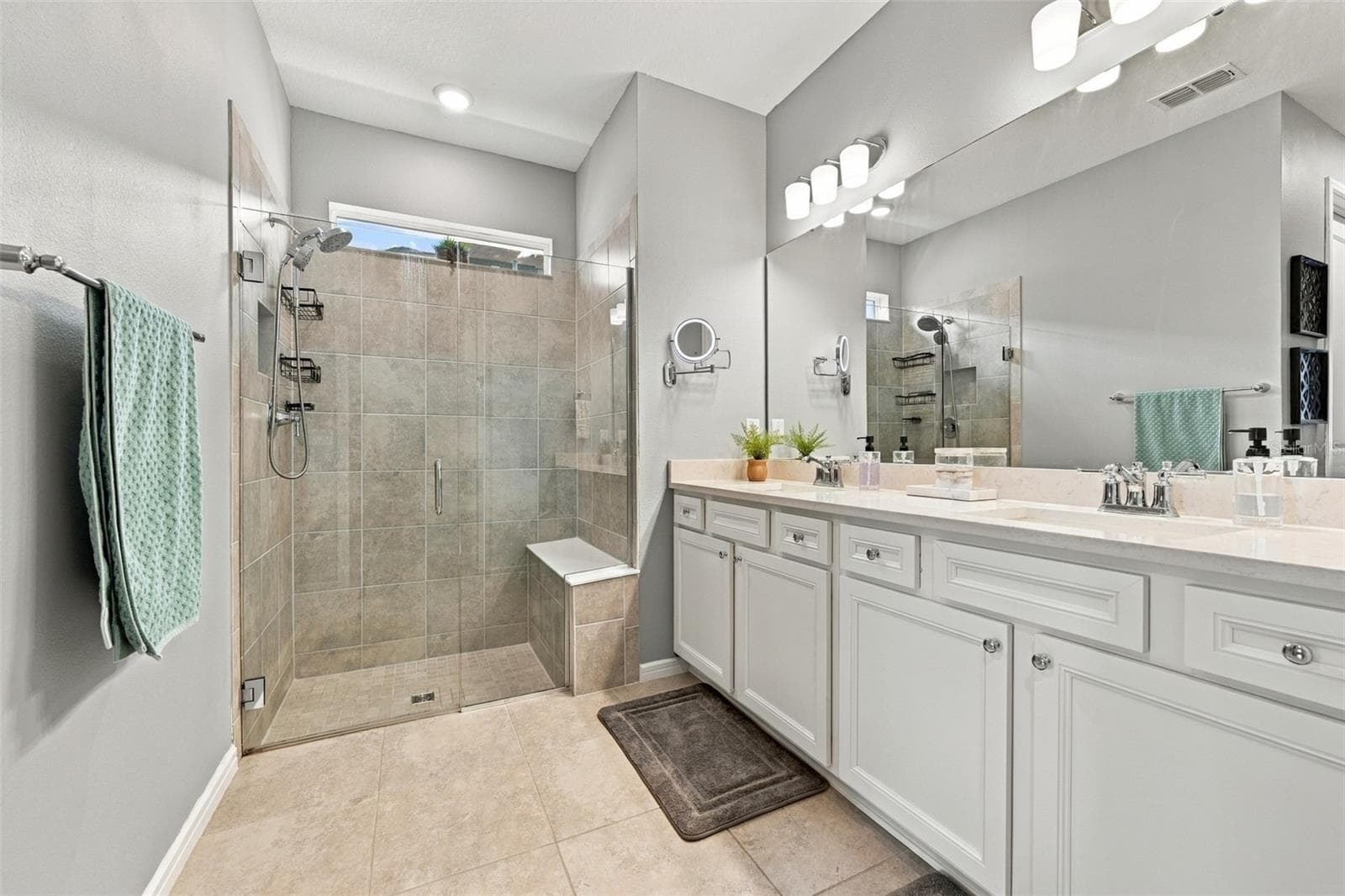 Primary ensuite luxurious bathroom with spacious vanity and multiple shower heads and shower bench. - 9260 BALLASTER POINTE LOOP, PARRISH