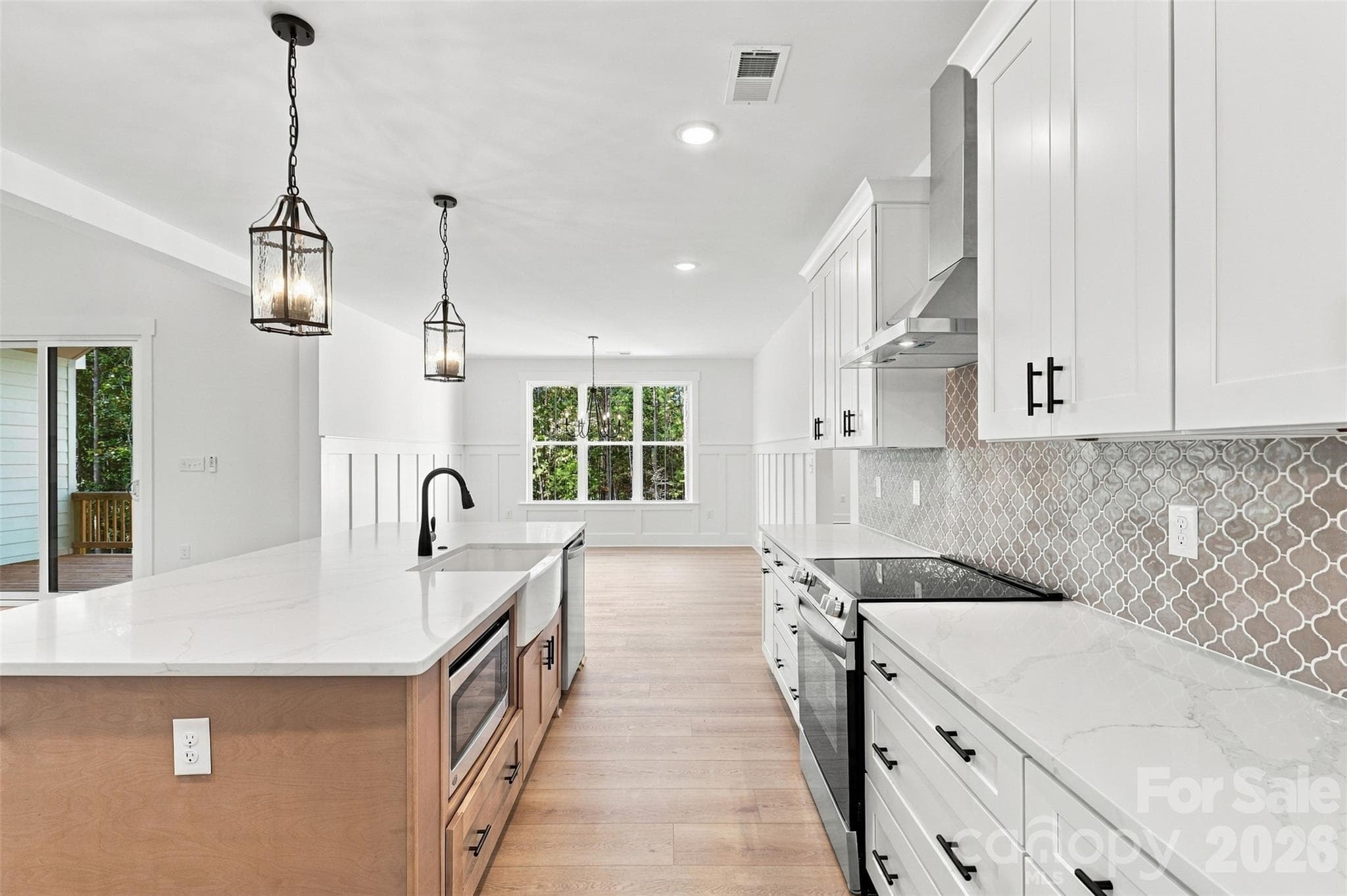 Kitchen- thoughtfully selected countertops, cabinetry, & backsplash. Walk-in pantry (w/ wood shelves!). Large island w/ porcelain farmhouse sink. Stainless steel hood vent. - 394 S NC 200 Highway, Stanfield