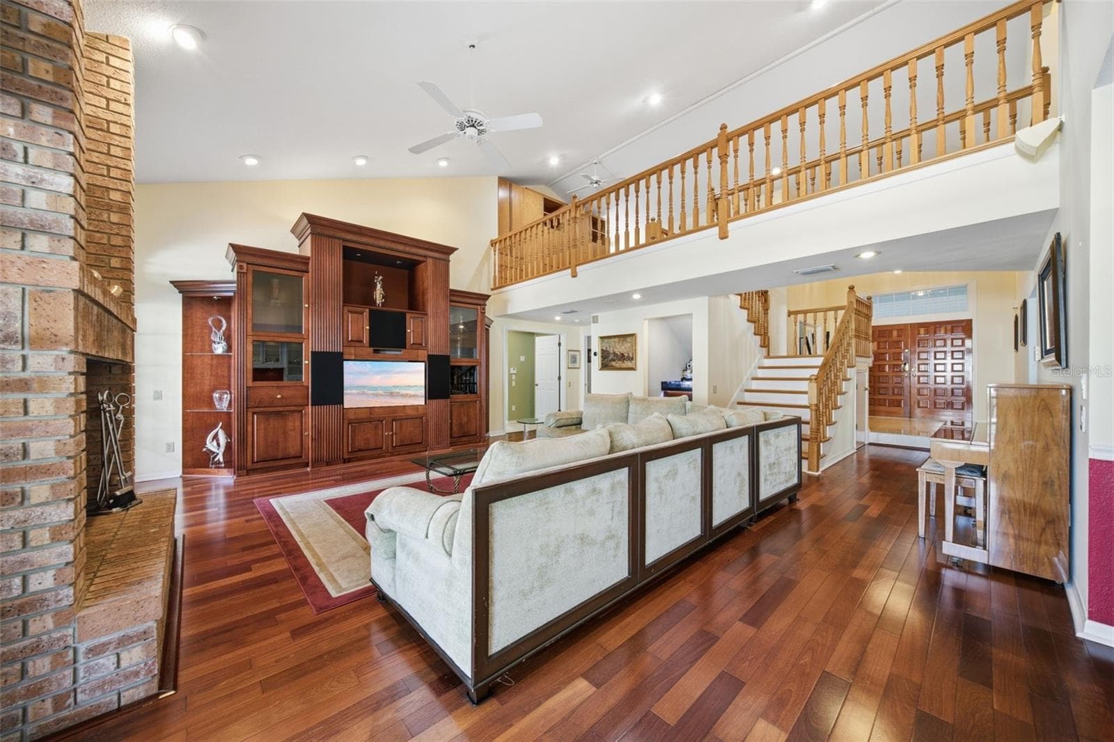 Great Room with wood flooring, built-ins and view to the Gallery / Loft area above - 12383 WINDTREE BLVD, SEMINOLE