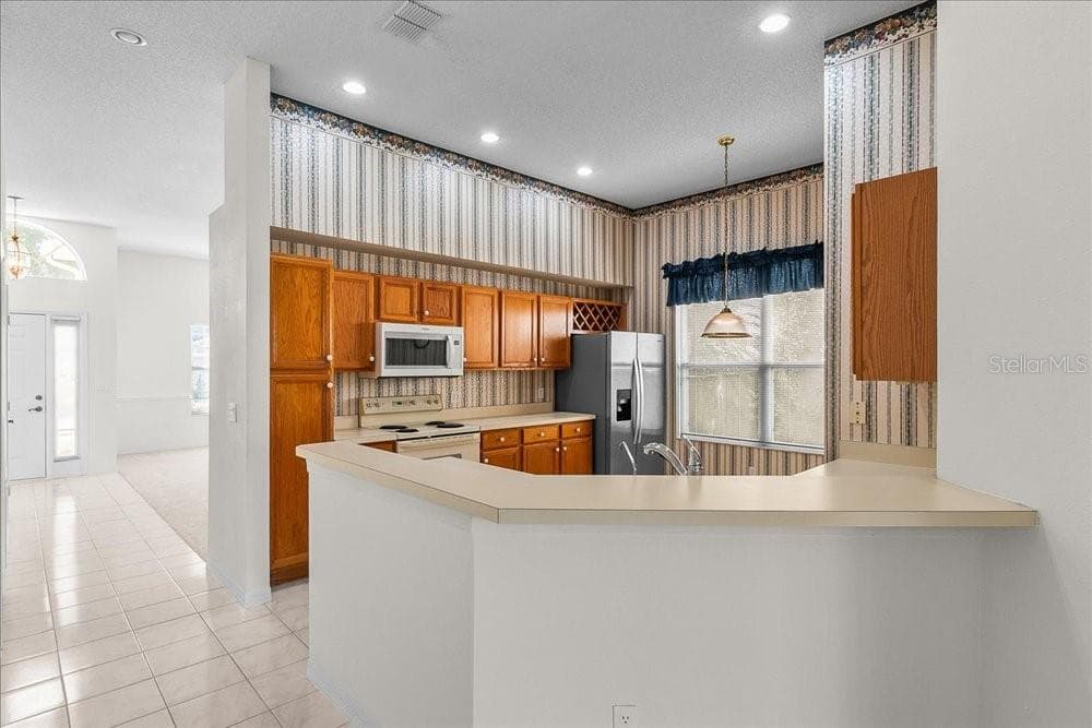 kitchen with breakfast bar and classic oak cabinets - 477 LAKEPARK TRL, OVIEDO