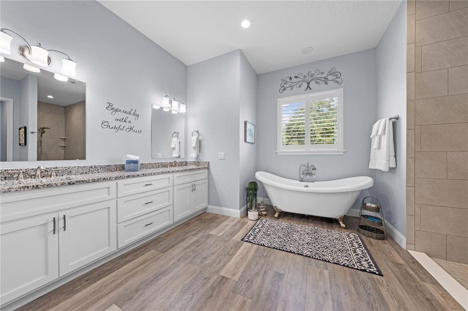 Primary bathroom with claw foot tub and double vanities with granite countertops. - 590 EDEN DR, ST CLOUD