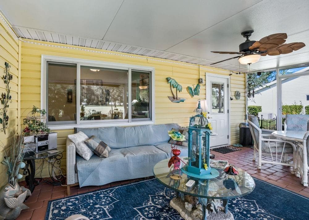 The covered, screened-in back lanai offers a relaxing outdoor retreat overlooking the golf course with views of the pond. Brick paver flooring, a tropical-style ceiling fan, and space for seating and dining make it an inviting spot for morning coffee or entertaining. - 17909 SE 99TH AVE, SUMMERFIELD