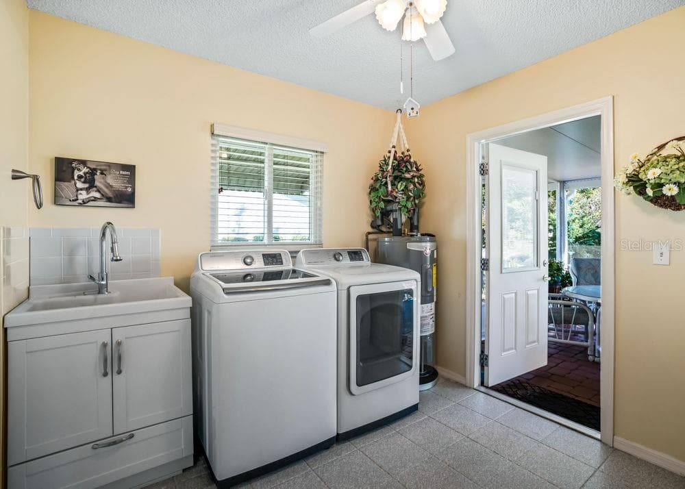 The indoor laundry room features refinished tile floors, an included washer and dryer, and a utility sink with cabinet storage. A window provides natural light, while a ceiling fan and direct access to the screened lanai add everyday convenience. - 17909 SE 99TH AVE, SUMMERFIELD