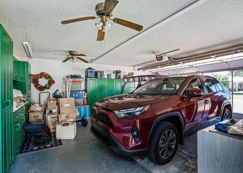 The two-car garage features an epoxy-finished floor, abundant cabinet storage, and two ceiling fans. An automatic garage door opener adds convenience, with space for parking, tools, and household essentials. - 17909 SE 99TH AVE, SUMMERFIELD