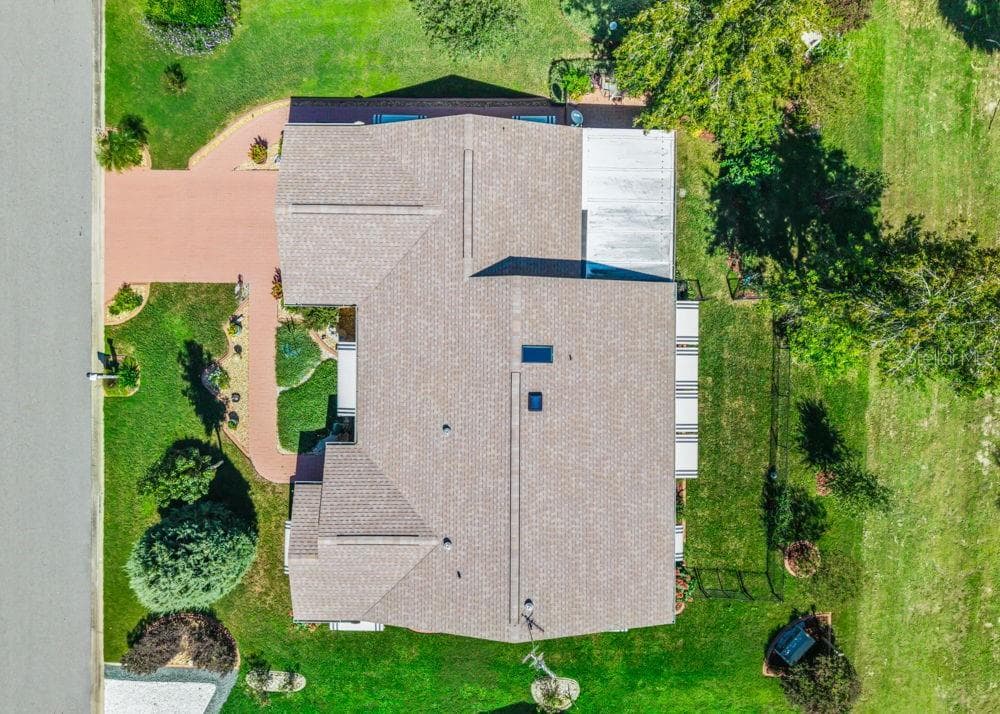 This overhead aerial view showcases the home’s roof, replaced in 2023, along with the brick-paver driveway and walkways. Lush landscaping, mature trees, and a fenced backyard complement the golf course setting. - 17909 SE 99TH AVE, SUMMERFIELD