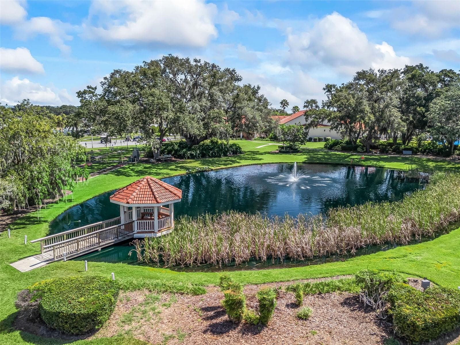 Spruce Creek South’s scenic community pond features a sparkling fountain and a charming gazebo reached by a wooden walkway. Mature oak trees, lush lawns, and landscaped gardens create a peaceful setting for relaxing and enjoying the view. - 17909 SE 99TH AVE, SUMMERFIELD