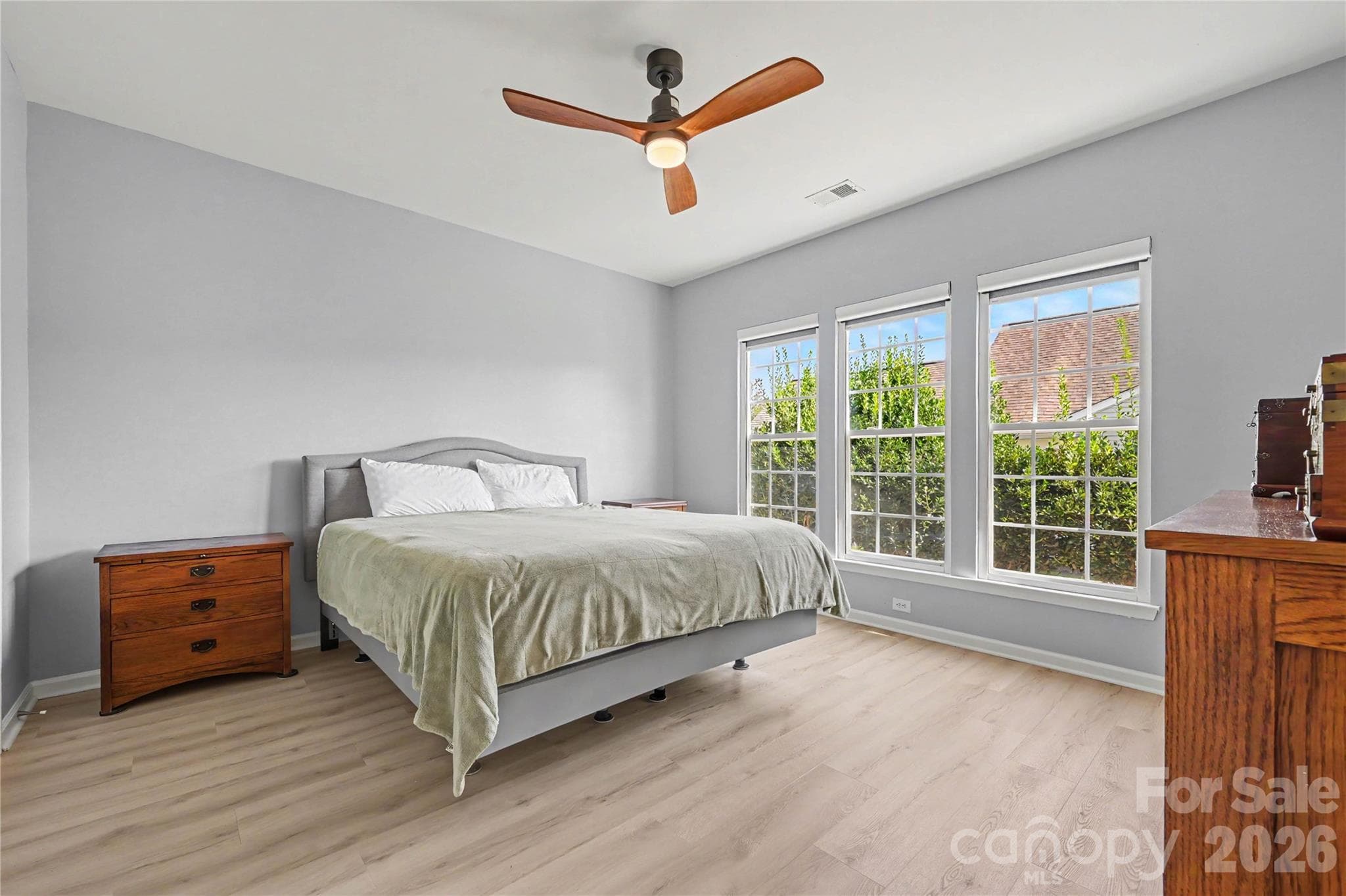 Another view of the Primary Bedroom showing the NEW LVP Flooring, neutral paint, CUSTOM POWER REMOTE WINDOW SHADES, and ceiling fan. - 3054 Azalea Drive, Indian Land