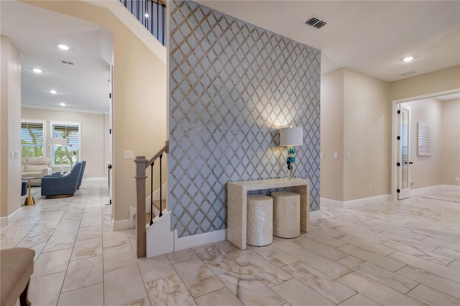 Statement accent wall highlights the entryway, with an open staircase and views into the main living areas. - 17600 LAKE STAR RD, WINTER GARDEN