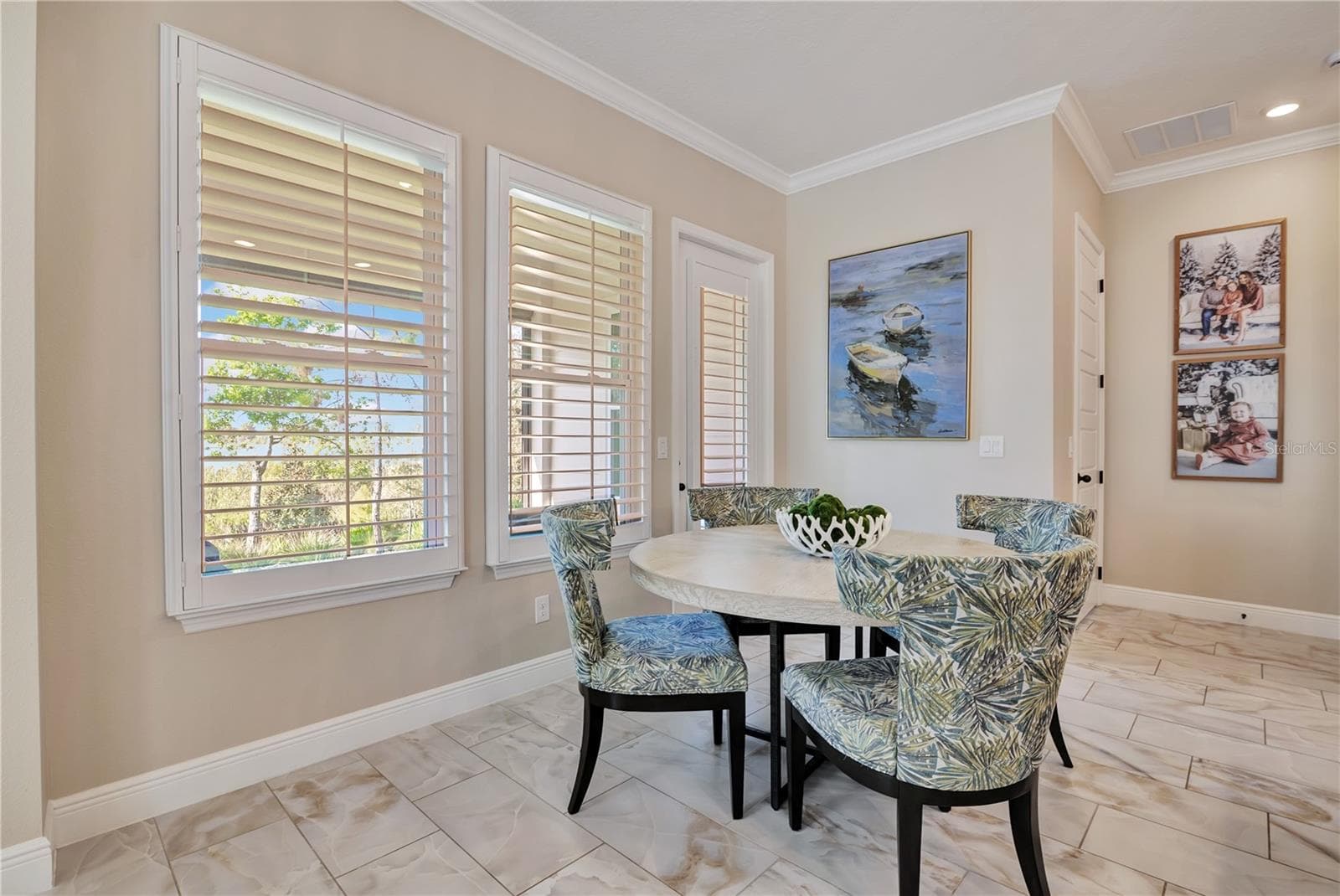 Sunlit breakfast nook surrounded by windows with plantation shutters, conveniently located beside the kitchen. - 17600 LAKE STAR RD, WINTER GARDEN