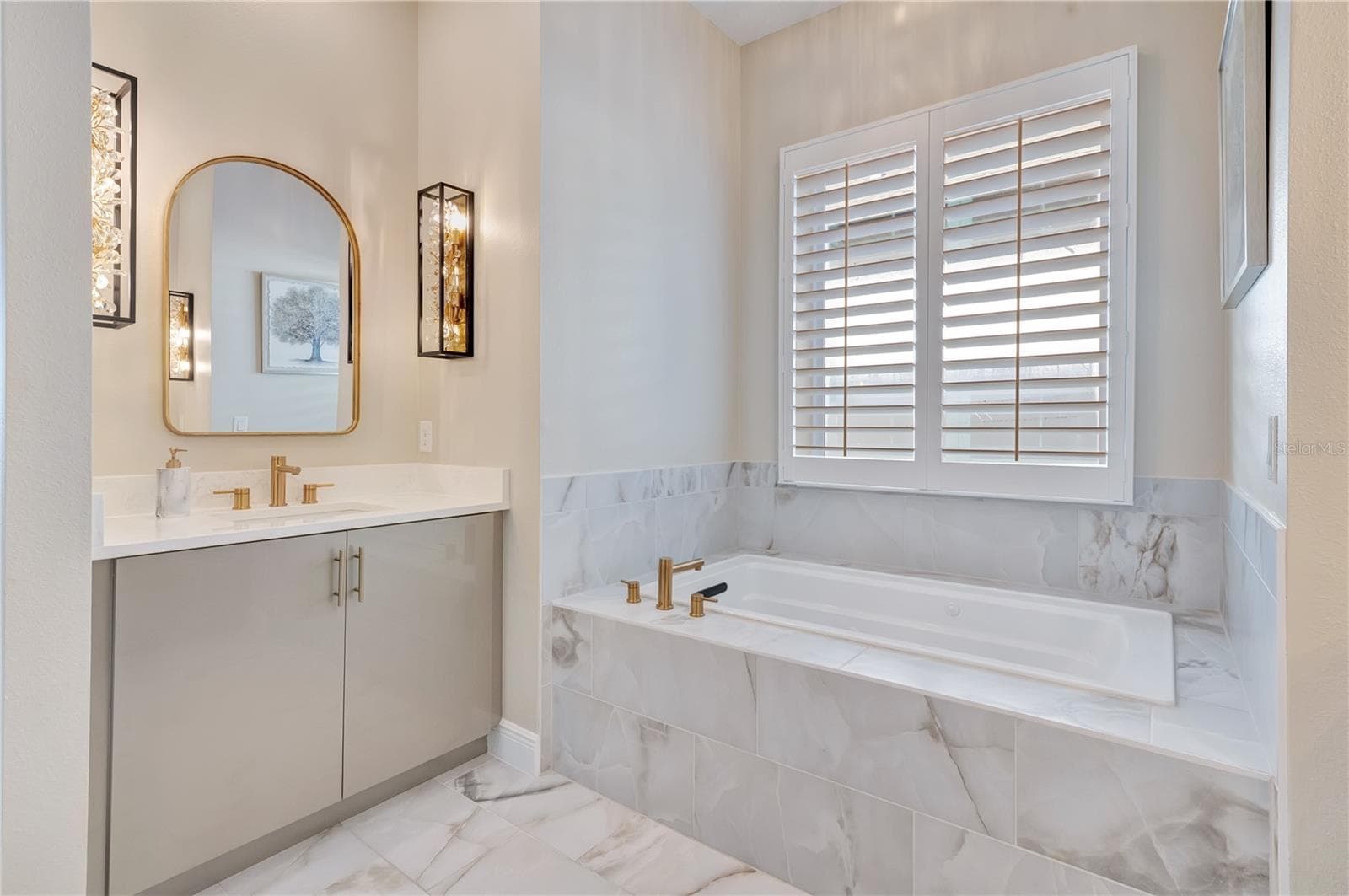 Elegant bathroom featuring a soaking tub, upgraded tile surrounds and a vanity accented by designer sconces. - 17600 LAKE STAR RD, WINTER GARDEN