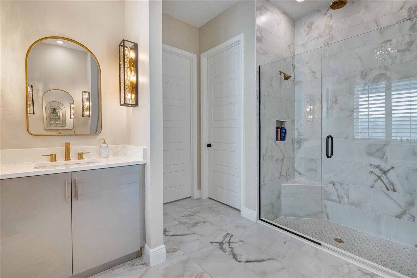 Upgraded bathroom featuring a glass-enclosed shower, floor-to-ceiling tile and a coordinating vanity with designer lighting. - 17600 LAKE STAR RD, WINTER GARDEN