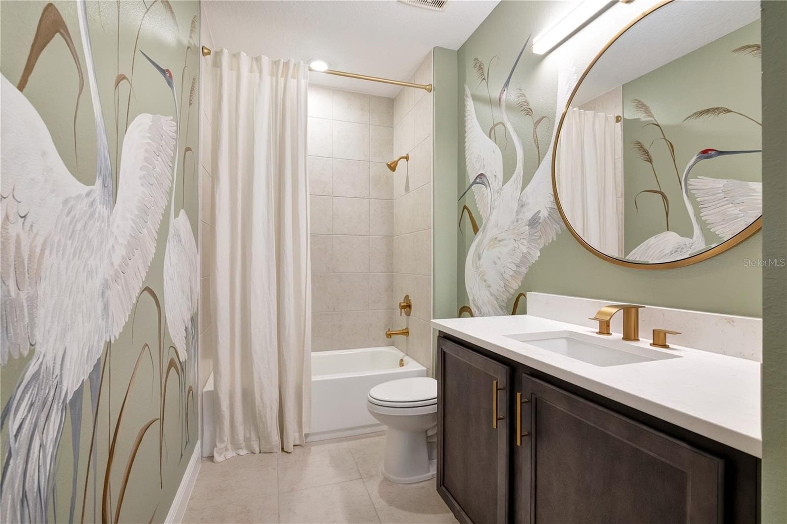 Beautifully styled bathroom featuring a bird-pattern accent wall, upgraded vanity and tub with shower. - 17600 LAKE STAR RD, WINTER GARDEN