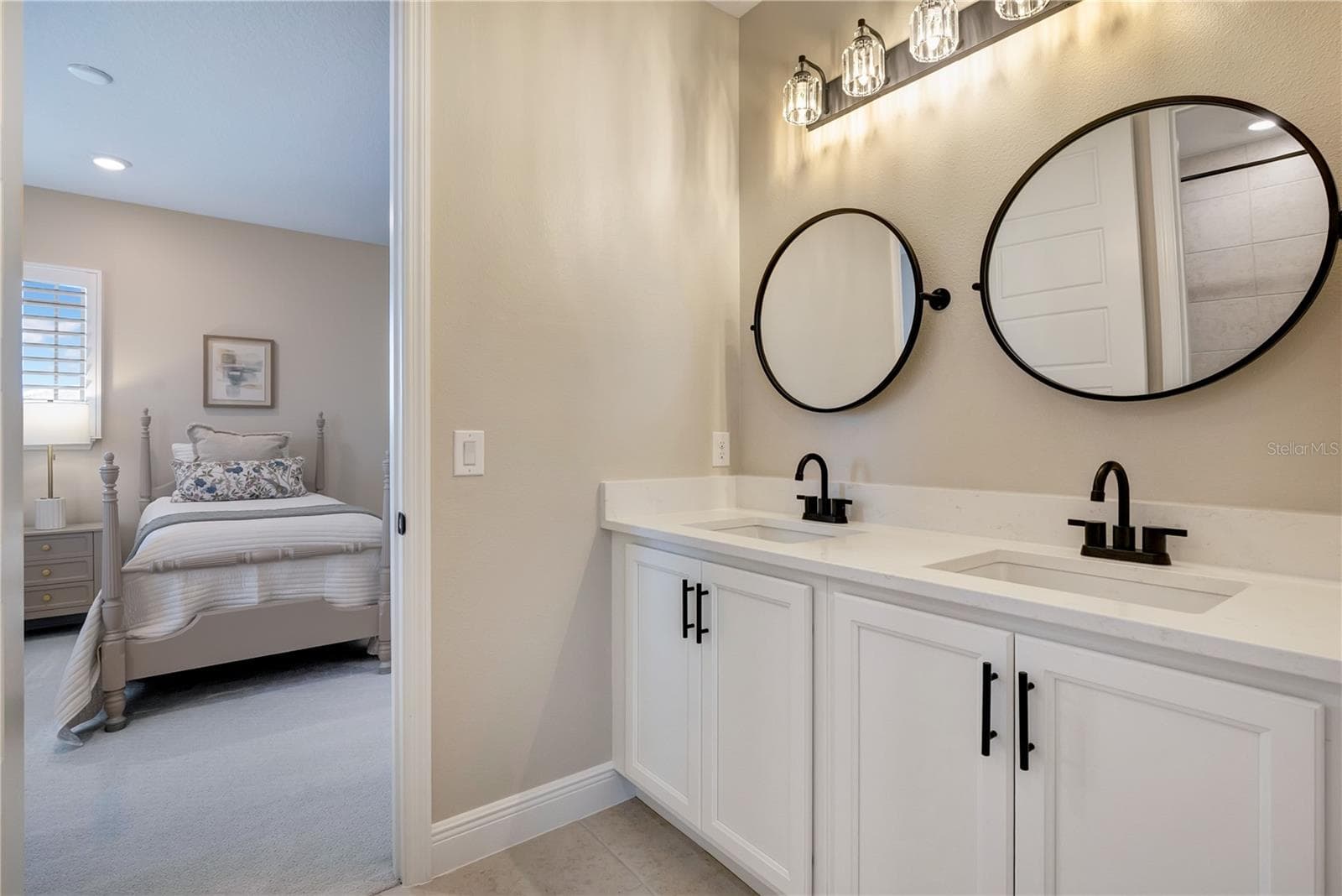 Double-sink vanity featuring white cabinetry, contrasting black fixtures and coordinating round mirrors. - 17600 LAKE STAR RD, WINTER GARDEN