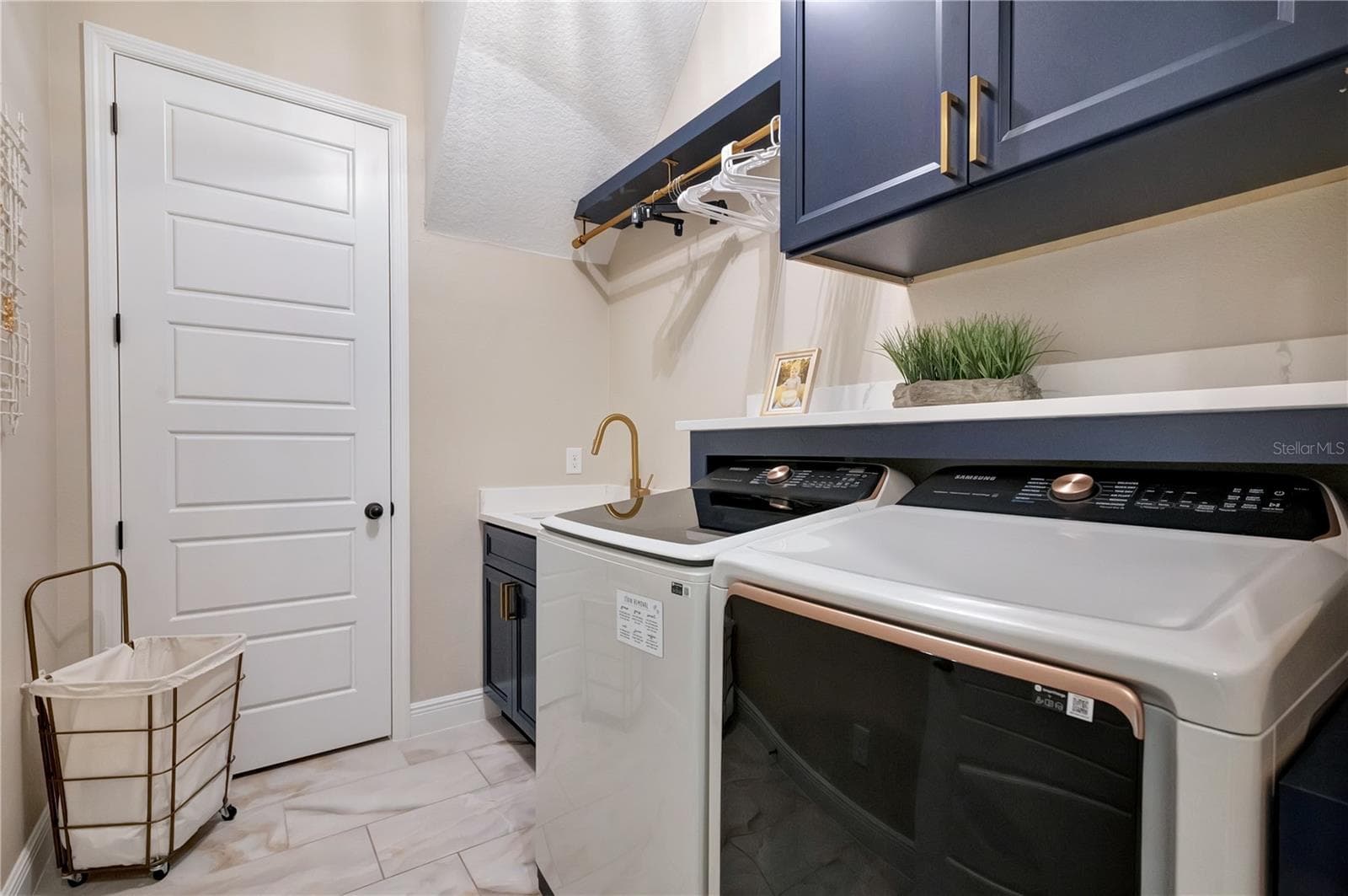 Custom laundry room featuring upgraded cabinetry, a utility sink, hanging rack and countertop above the washer and dryer. - 17600 LAKE STAR RD, WINTER GARDEN