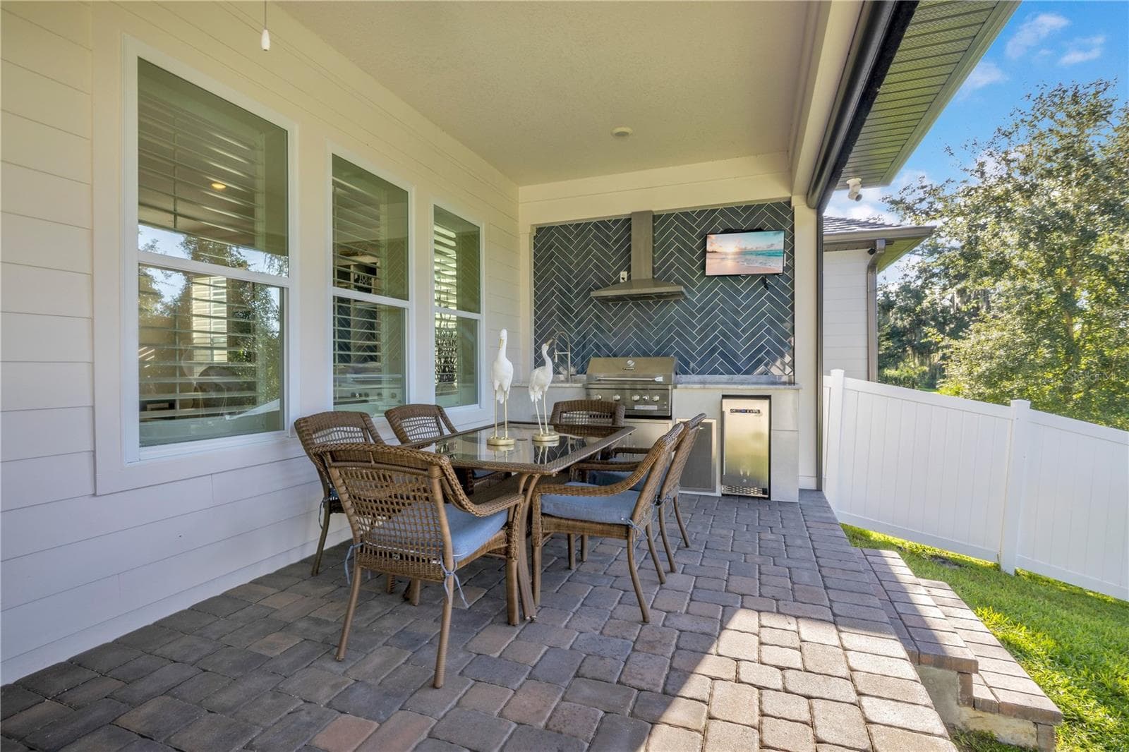 Covered outdoor dining area with a custom summer kitchen, built-in grill and beverage refrigerator. - 17600 LAKE STAR RD, WINTER GARDEN