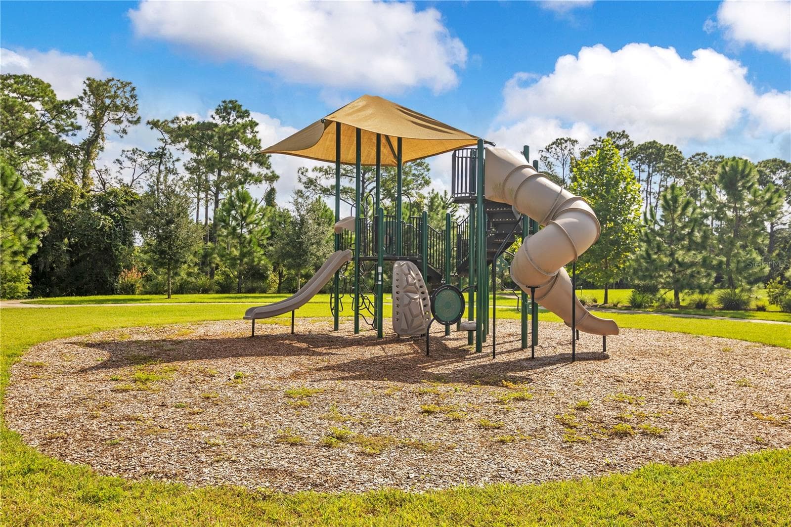 Community playground featuring climbing structures and slides in an open grassy setting. - 17600 LAKE STAR RD, WINTER GARDEN