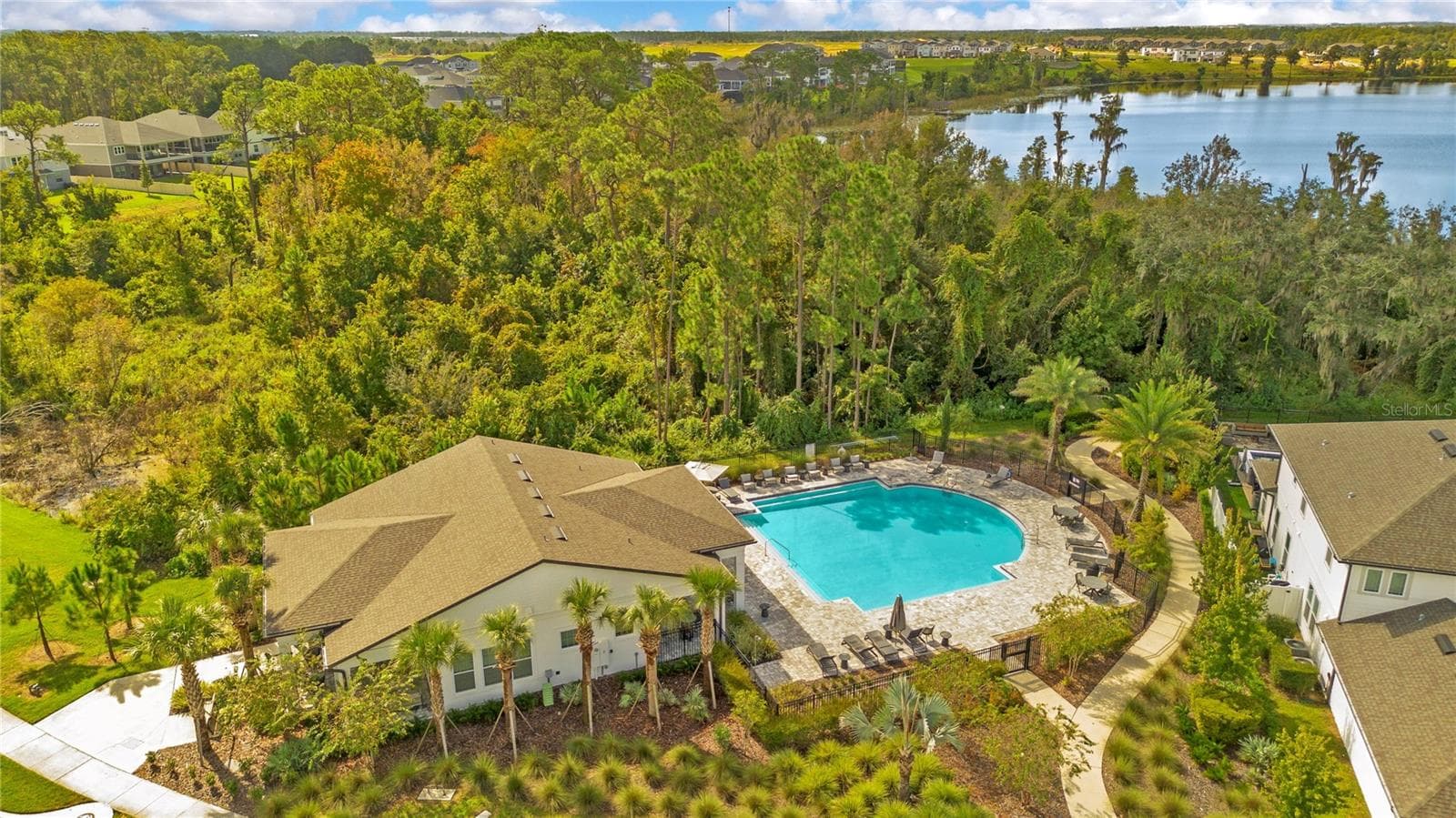 Community pool and clubhouse surrounded by landscaped grounds and mature trees. - 17600 LAKE STAR RD, WINTER GARDEN